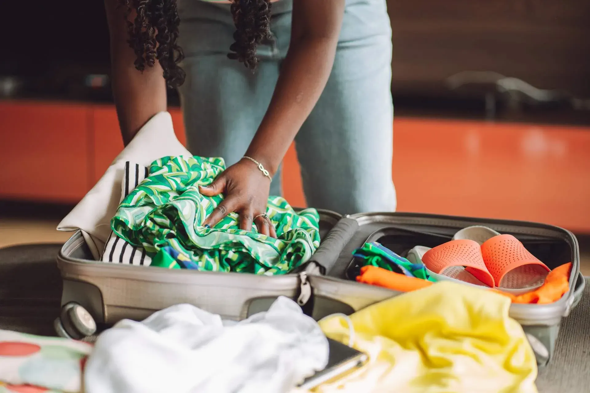 a woman packing some clothes into her suitcase