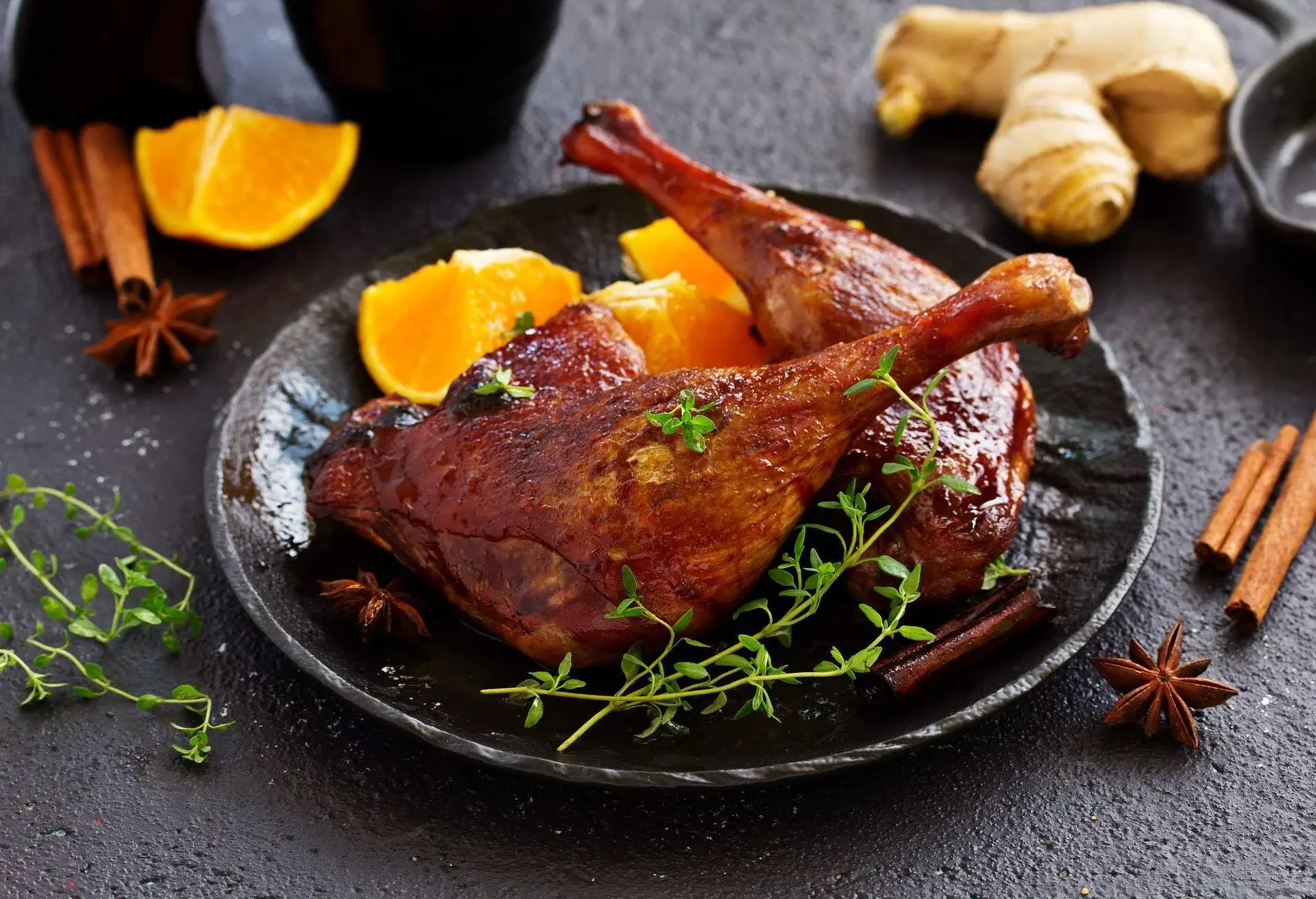 Black plate with duck confit, orange slices and herbs