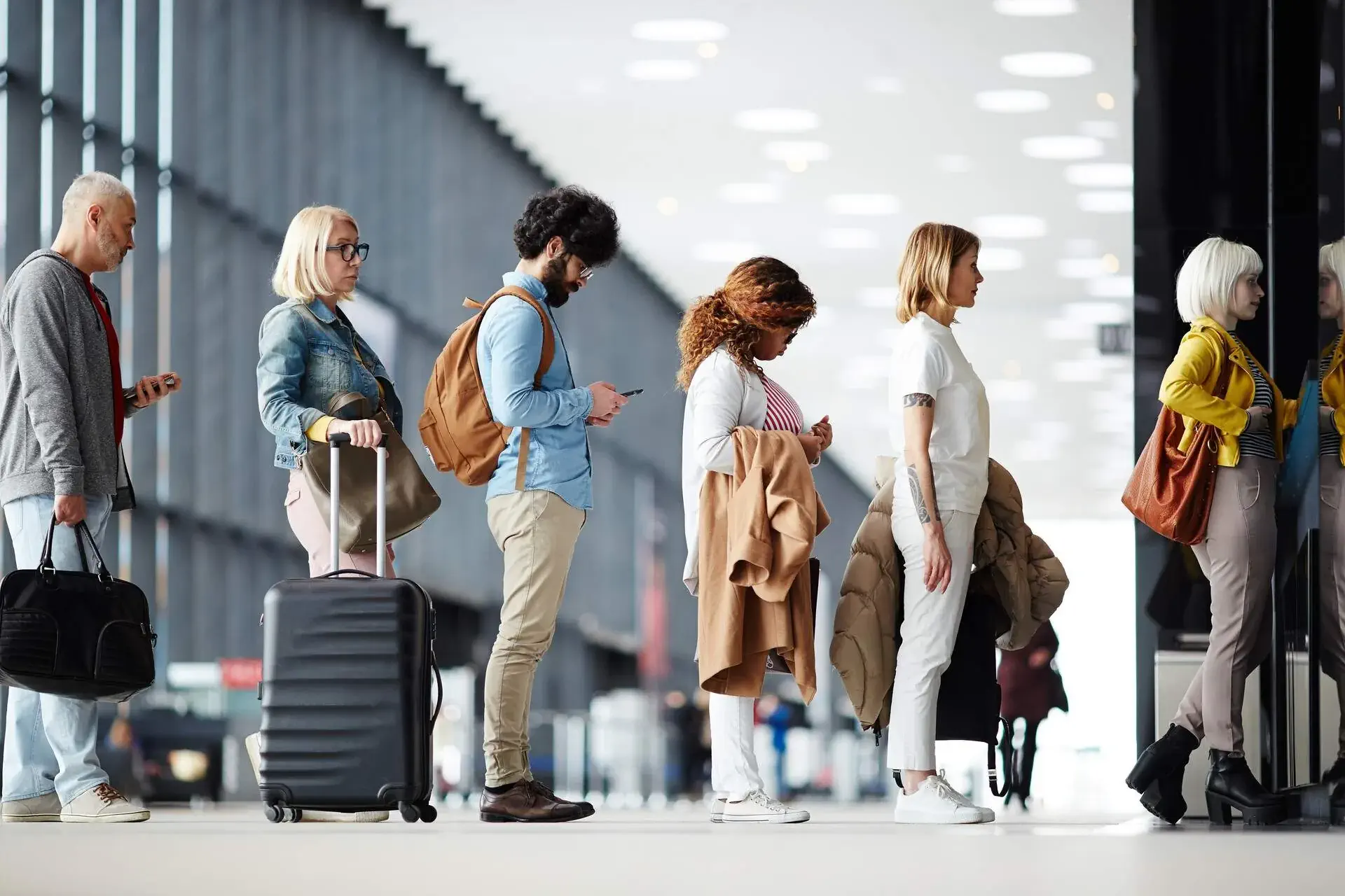 Six people standing and waiting in a straight line at the airport 