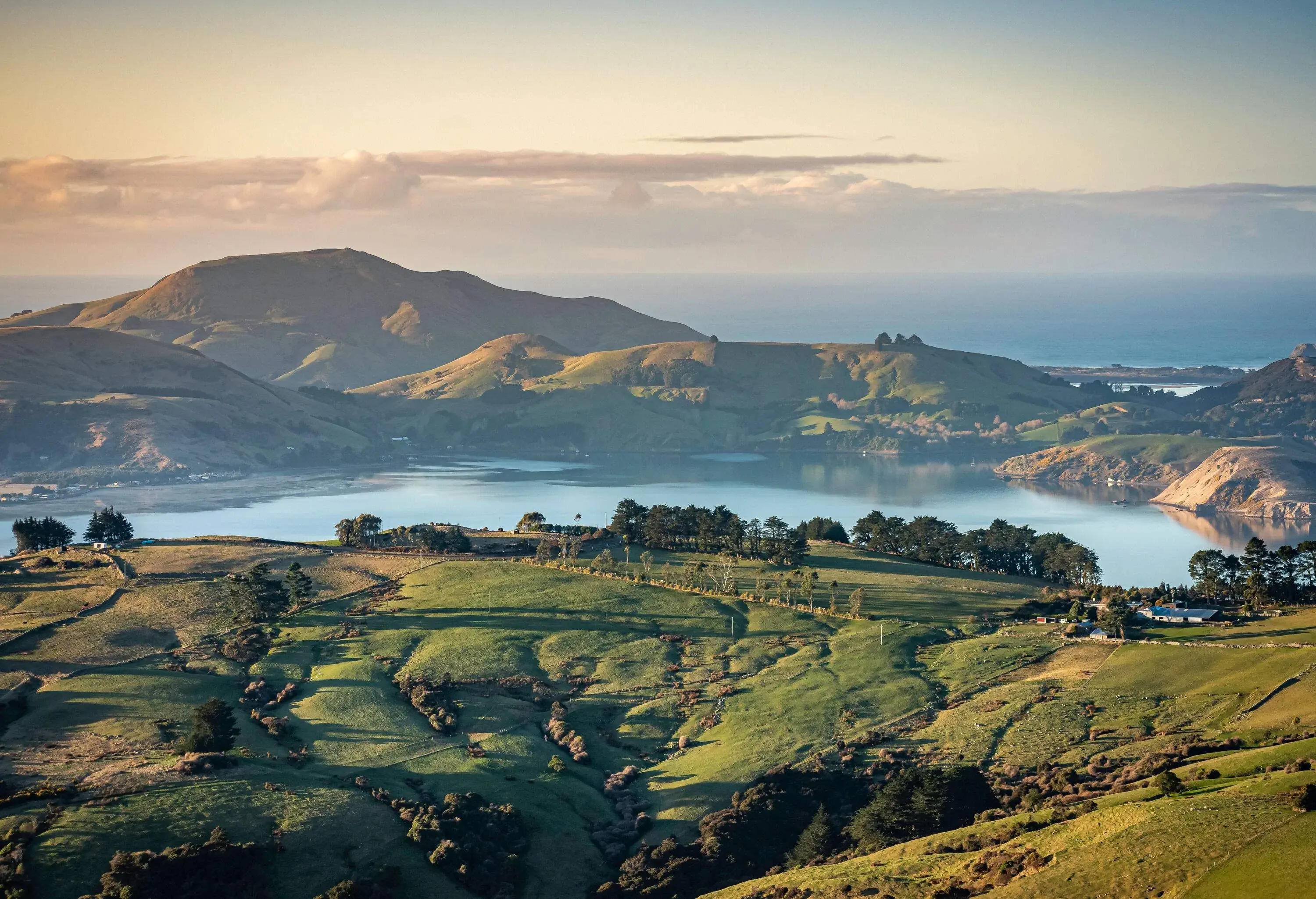 A picturesque landscape of rolling green hills and fertile farmland gently embraces a serene lake.