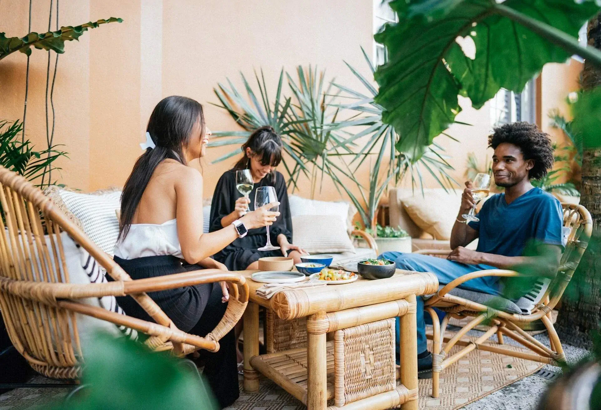 Three friends enjoying wine and snacks at a tropical all inclusive resort.