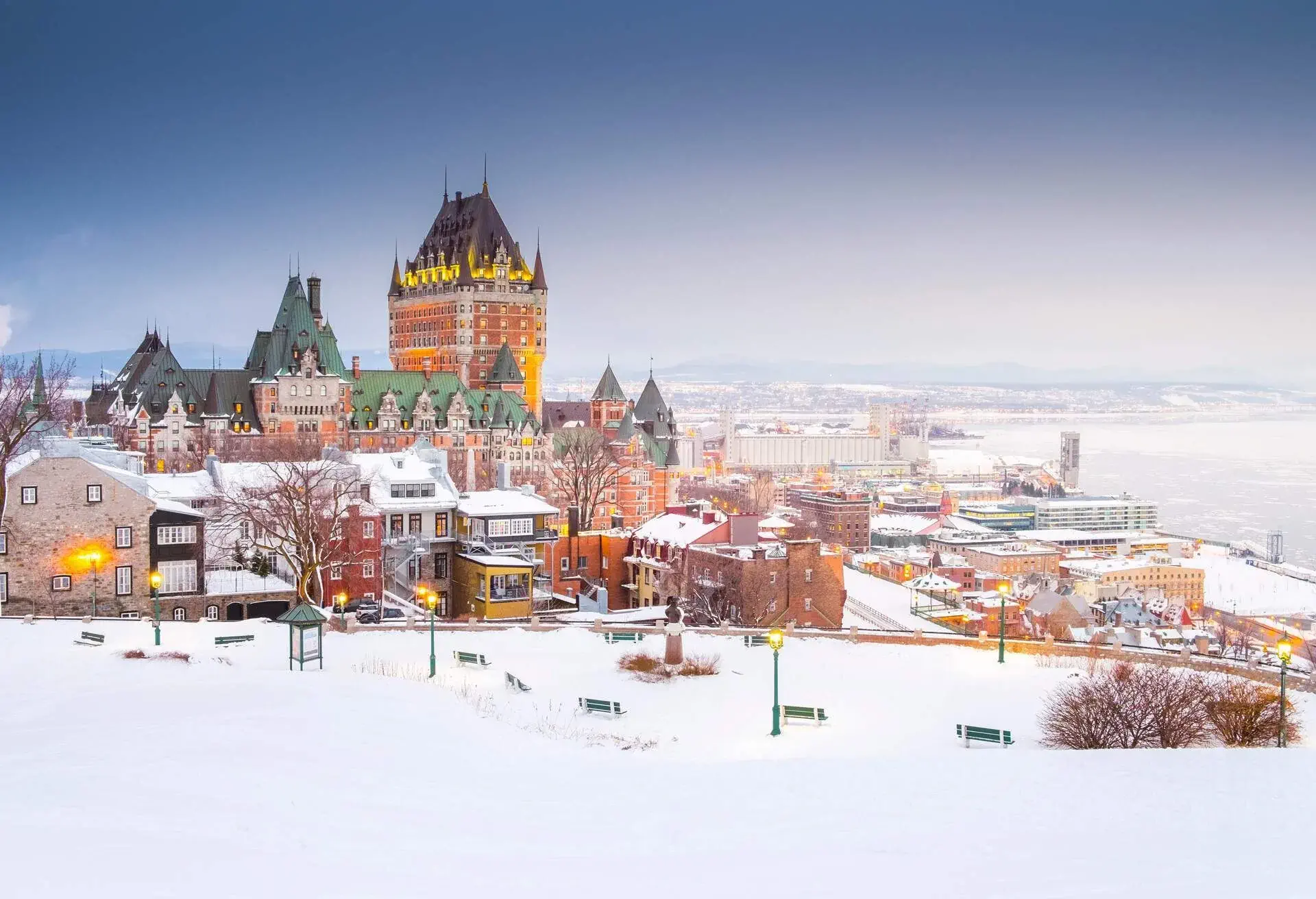 A luxurious hotel overlooking a lake and dominating over houses and buildings during winter season.