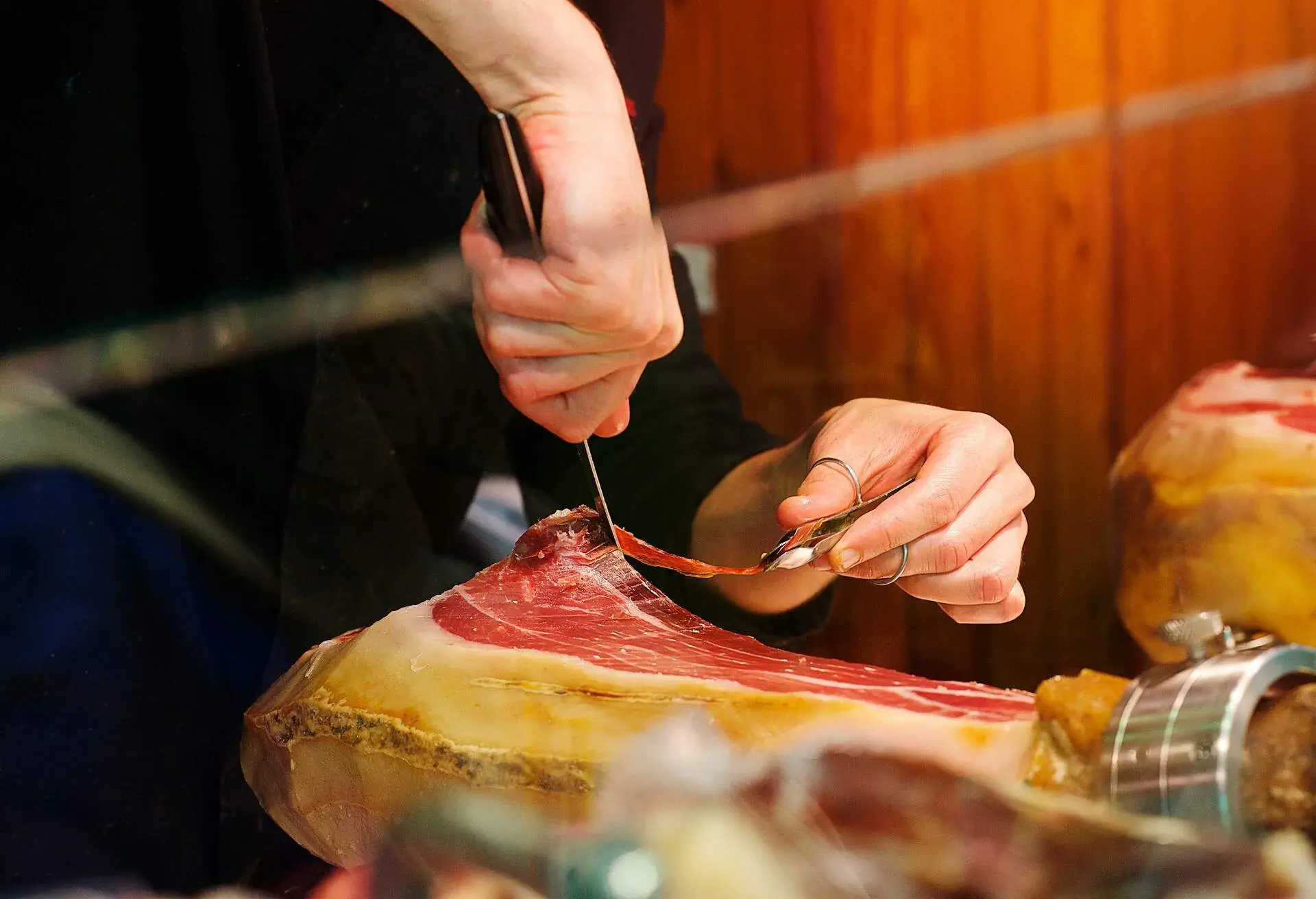 Hands cutting slices of Spanish Jamon