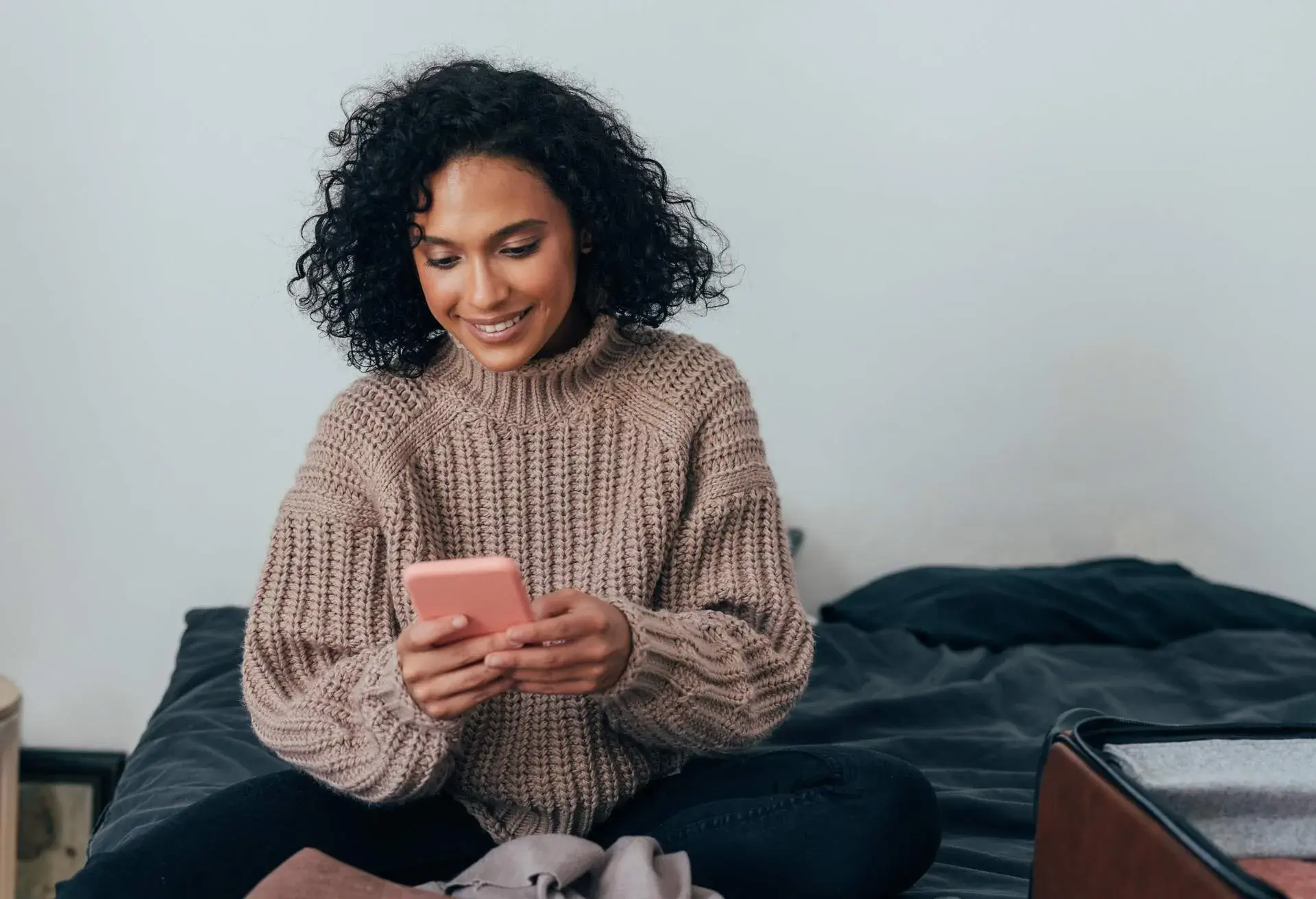 A woman smiling while looking at her smartphone