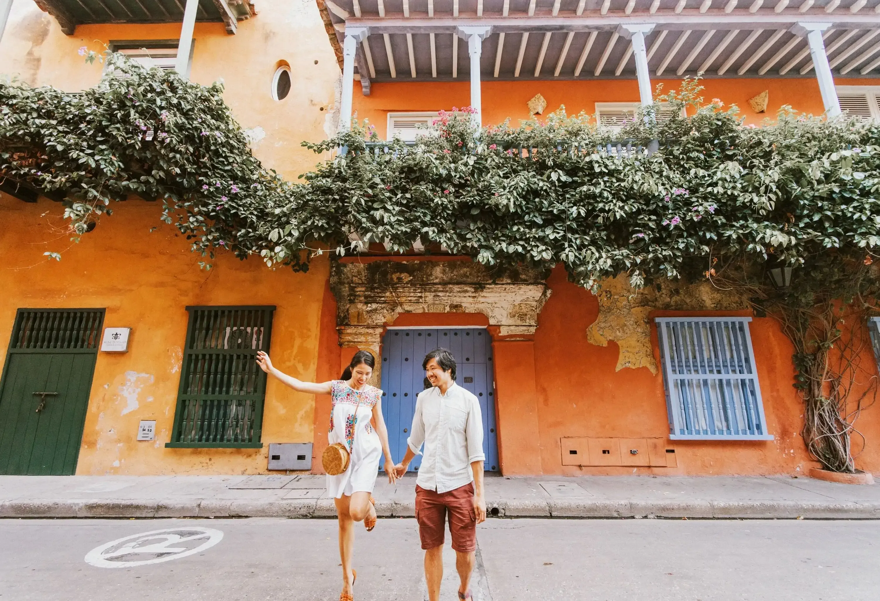Happy couple standing in the street in front of orange colonial building