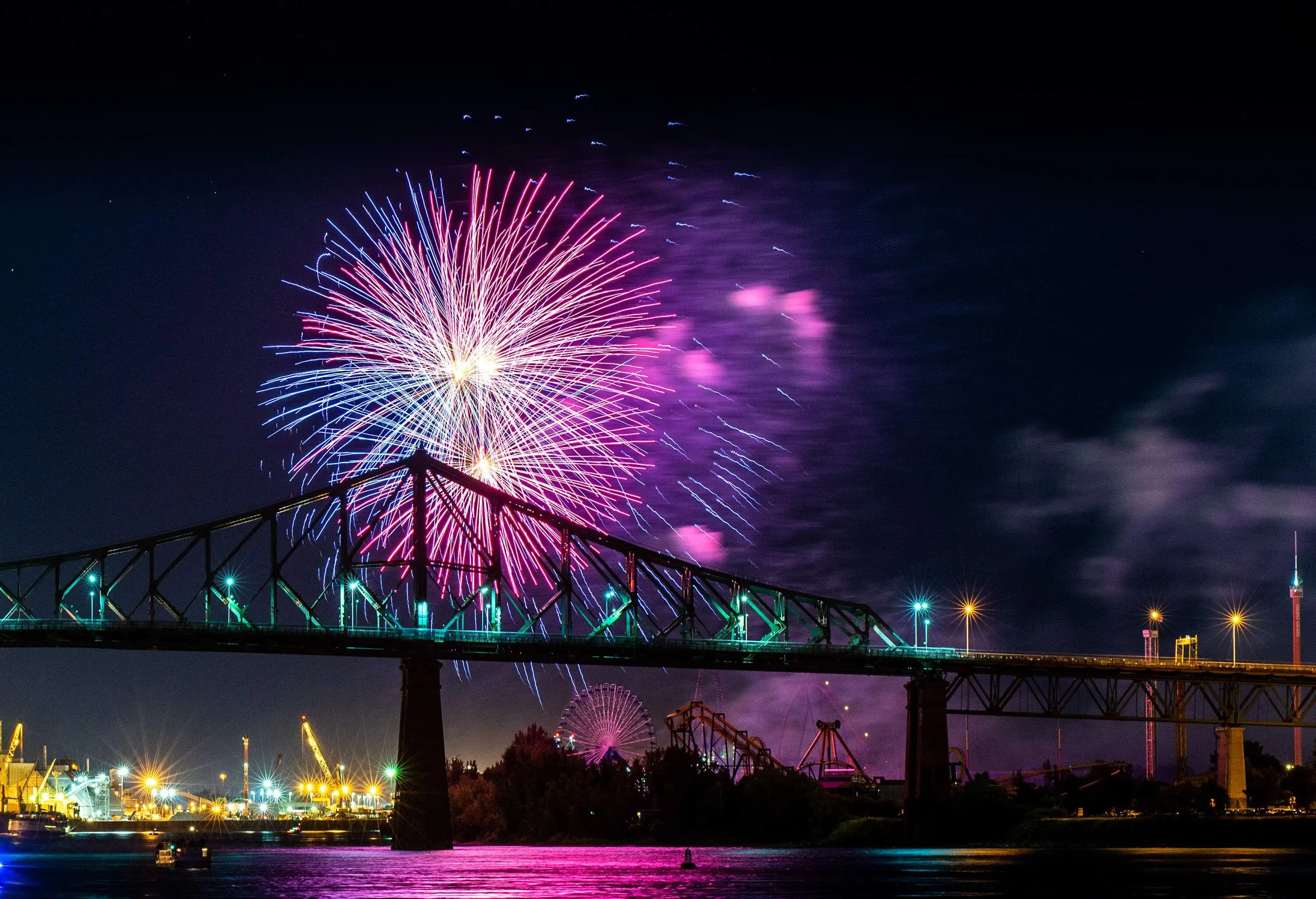 Vibrant, colourful fireworks lit up the dark sky above a cantilever bridge.