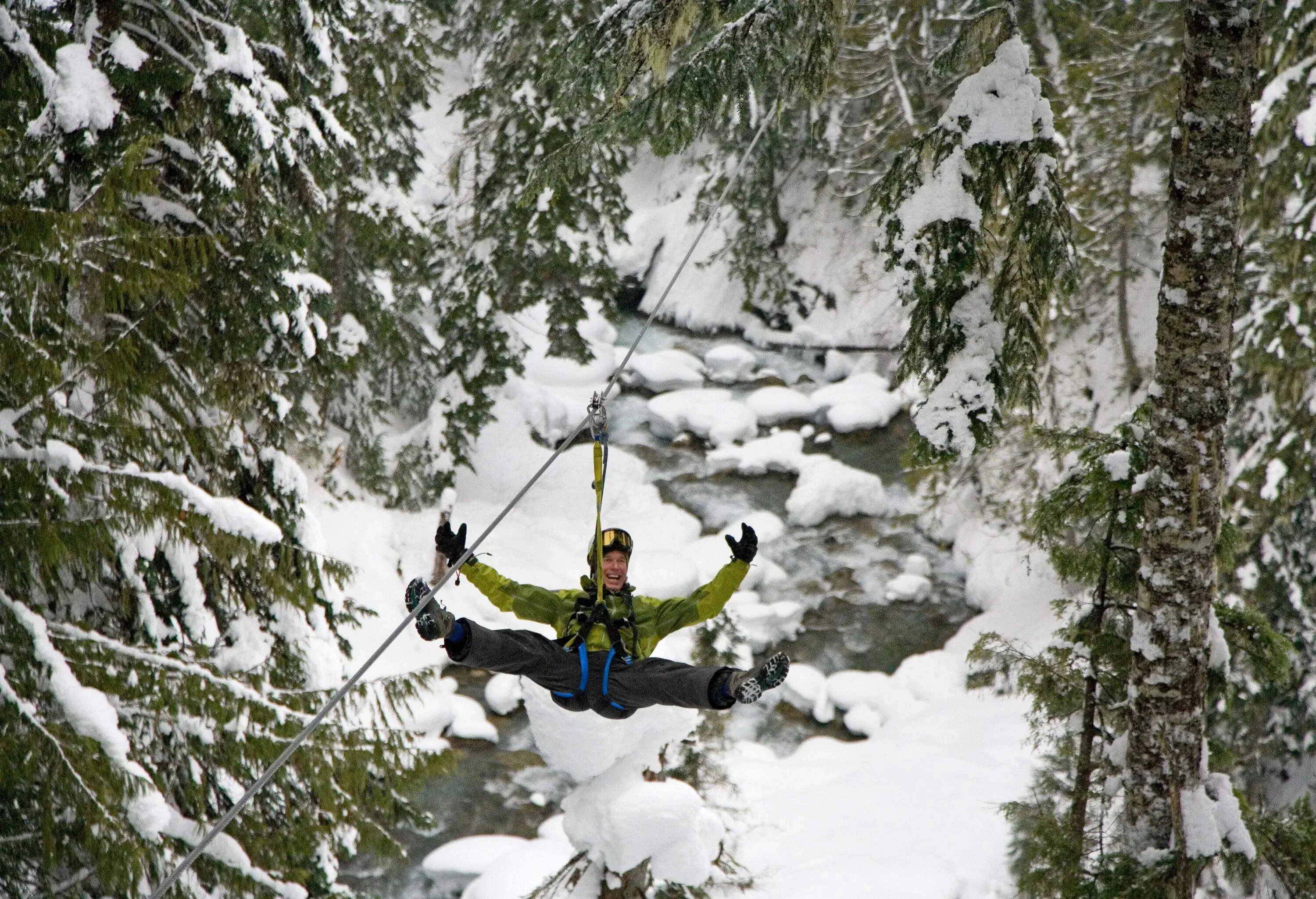 A person dressed in winter gear appears to be having the time of their life as they zip along a wintry course with a broad smile and arms wide open in pure exhilaration.