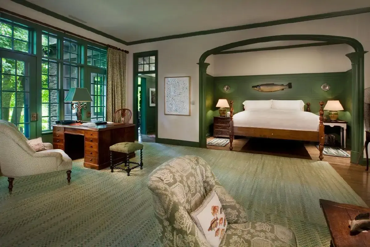 Elegant bedroom with green walls, large windows, a big bed, and traditional wooden furniture.