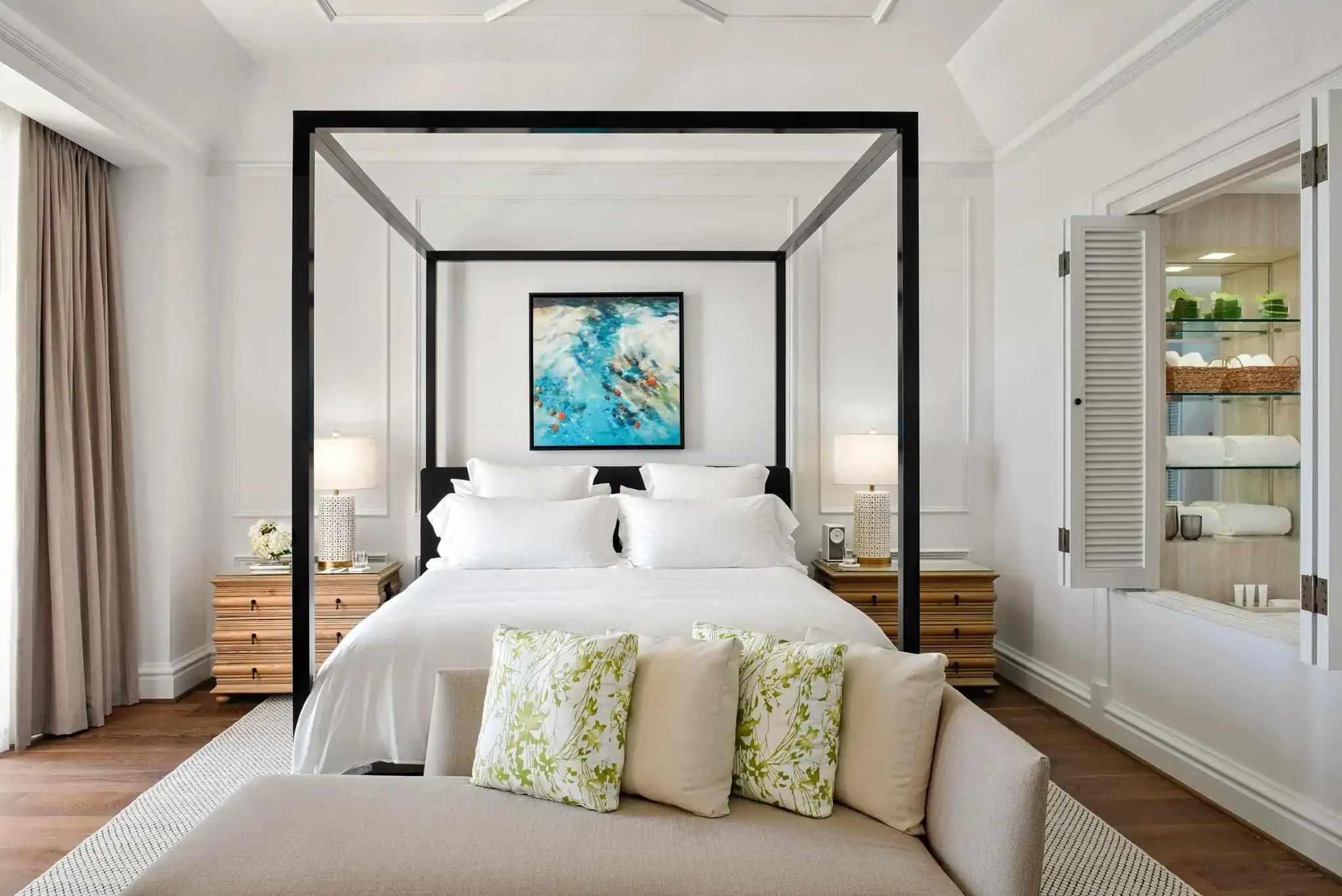 Interior view of a classic modern airy hotel room with a white and pastel colour scheme and four poster bed
