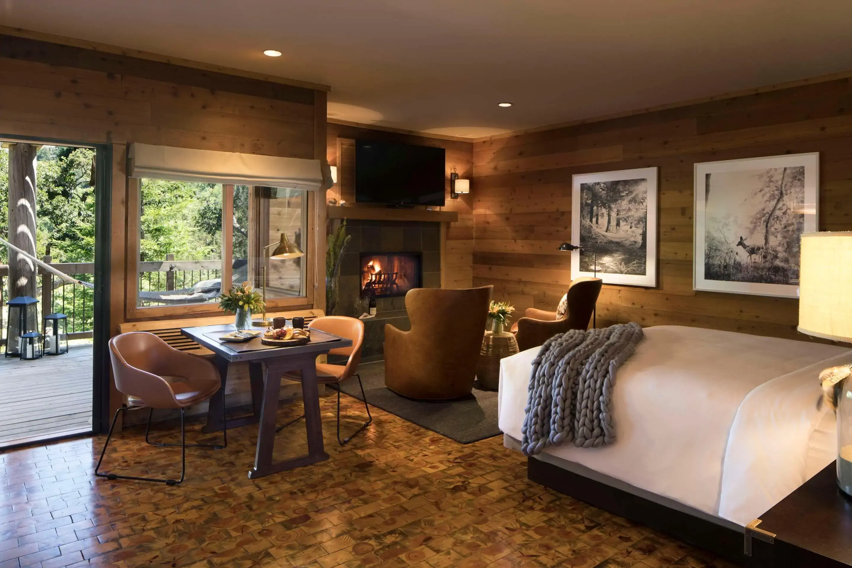 Cozy bedroom interior with fireplace, wooden walls, and a view of the deck outside.