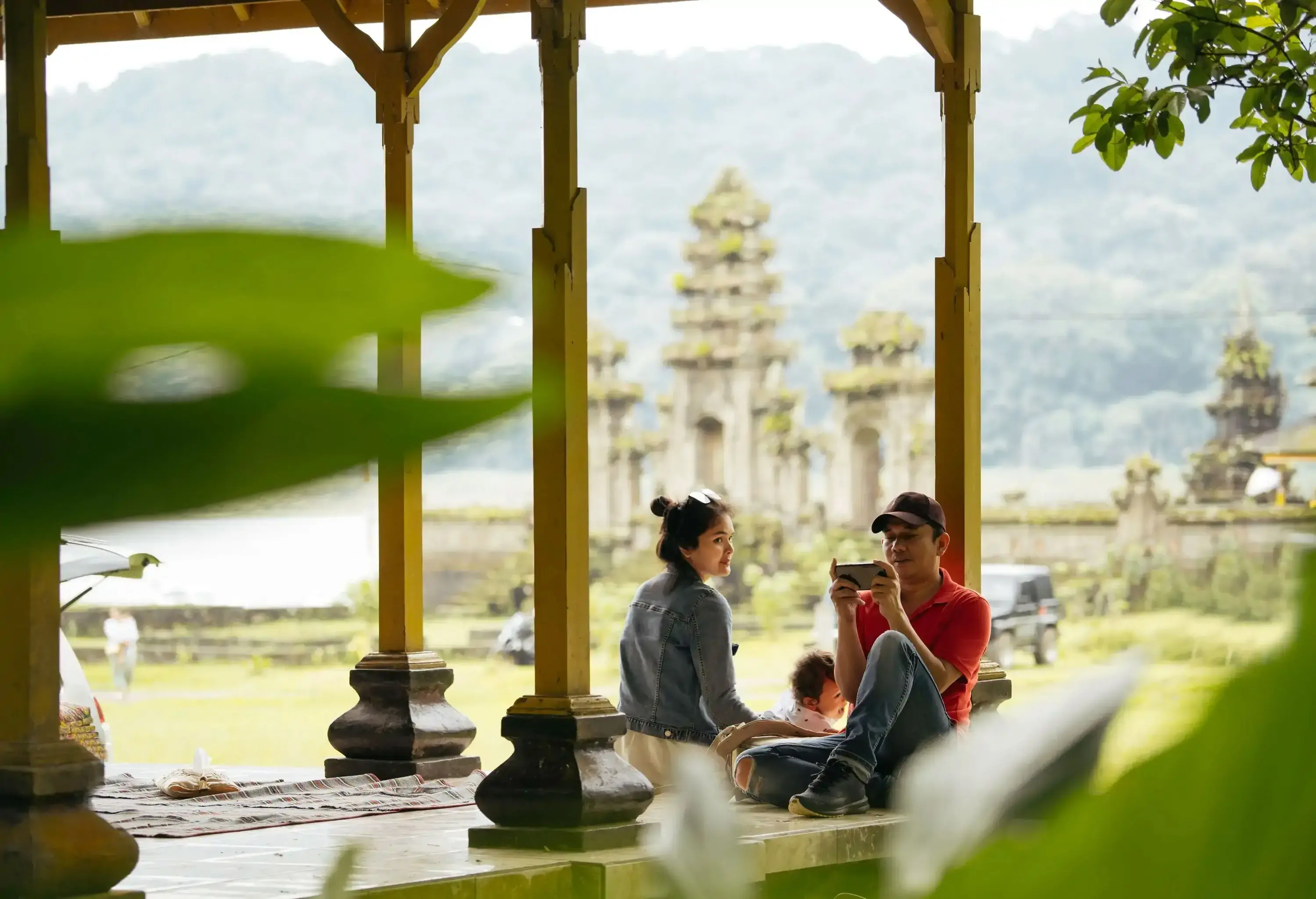 Asia, Indonesia, Bali, asian family sitting inside pavillion  enjoy the travel, in front of Tamblingan water temple, while sightseeing.