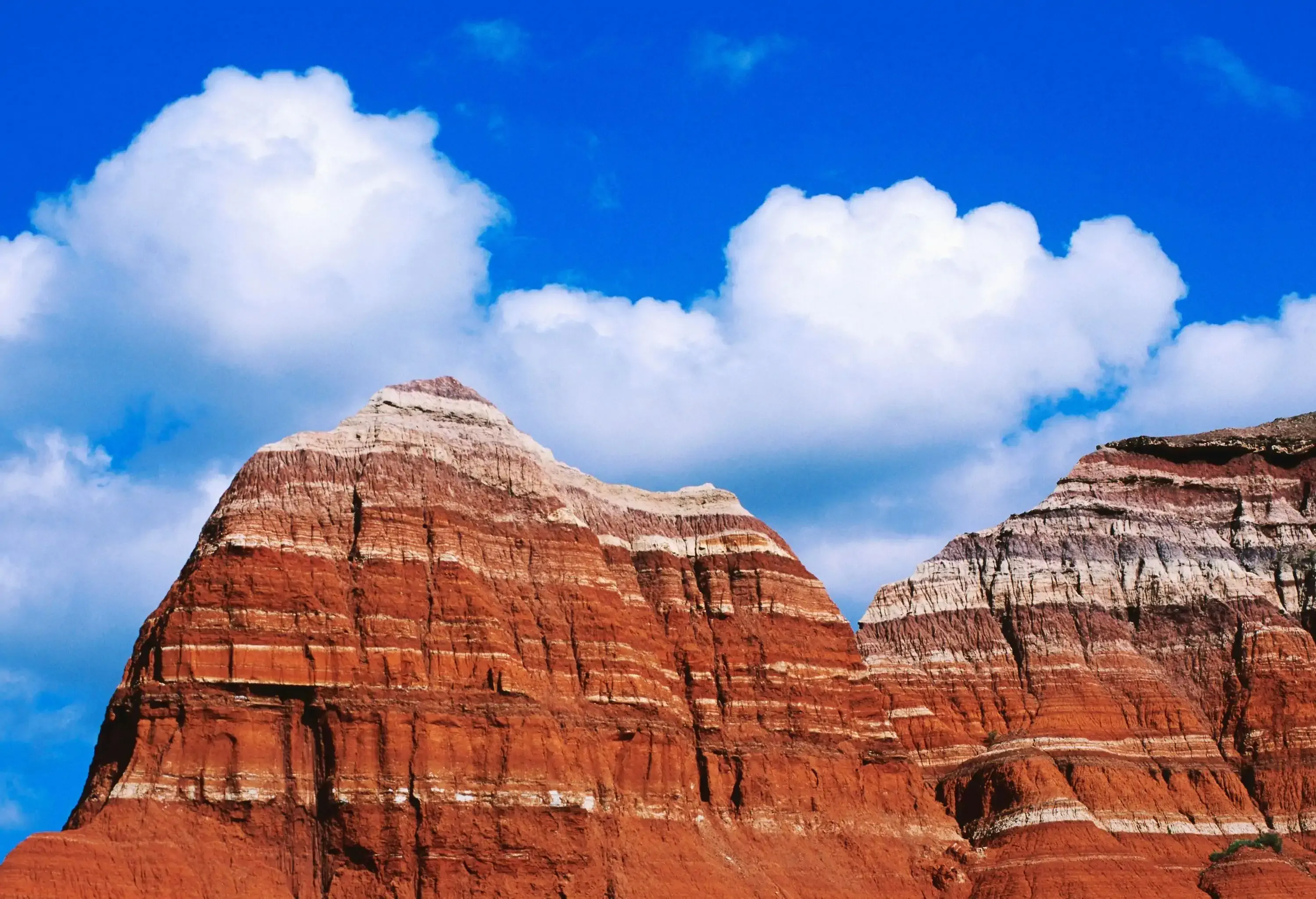 A steep-sided canyon with layered bands of bedrock visible beneath the bright sky.