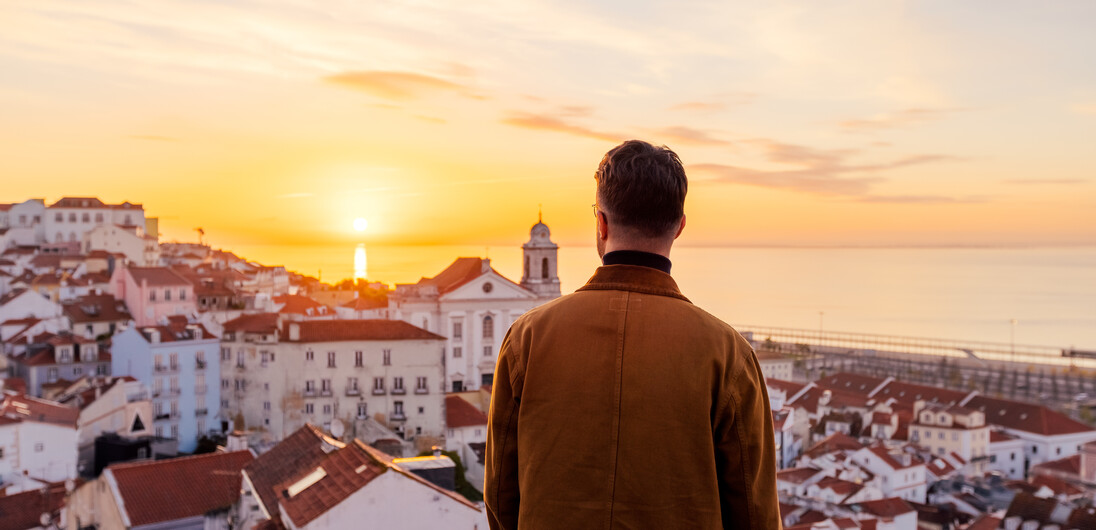 DEST_PORTUGAL_LISBON_MAN_LOOKING_AT_SKYLINE_SUNRISE_GettyImages-1443598818_Universal_Within%20usage%20period_99766.jpg
