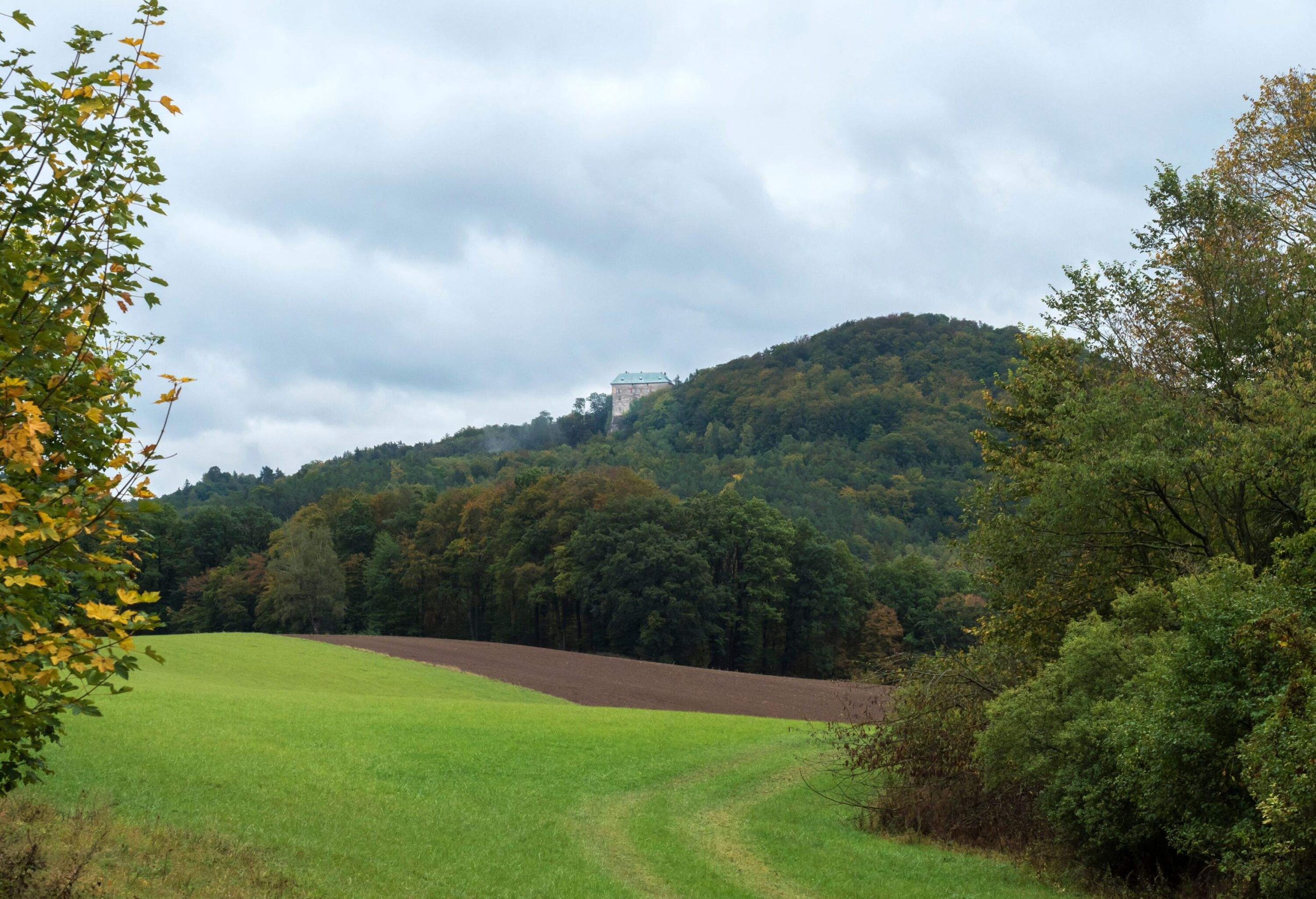 Meadow, fields and forest with view of medieval castle Houska. Autumn, moody sky. Landscape in Kokorinsko, Czech Republic