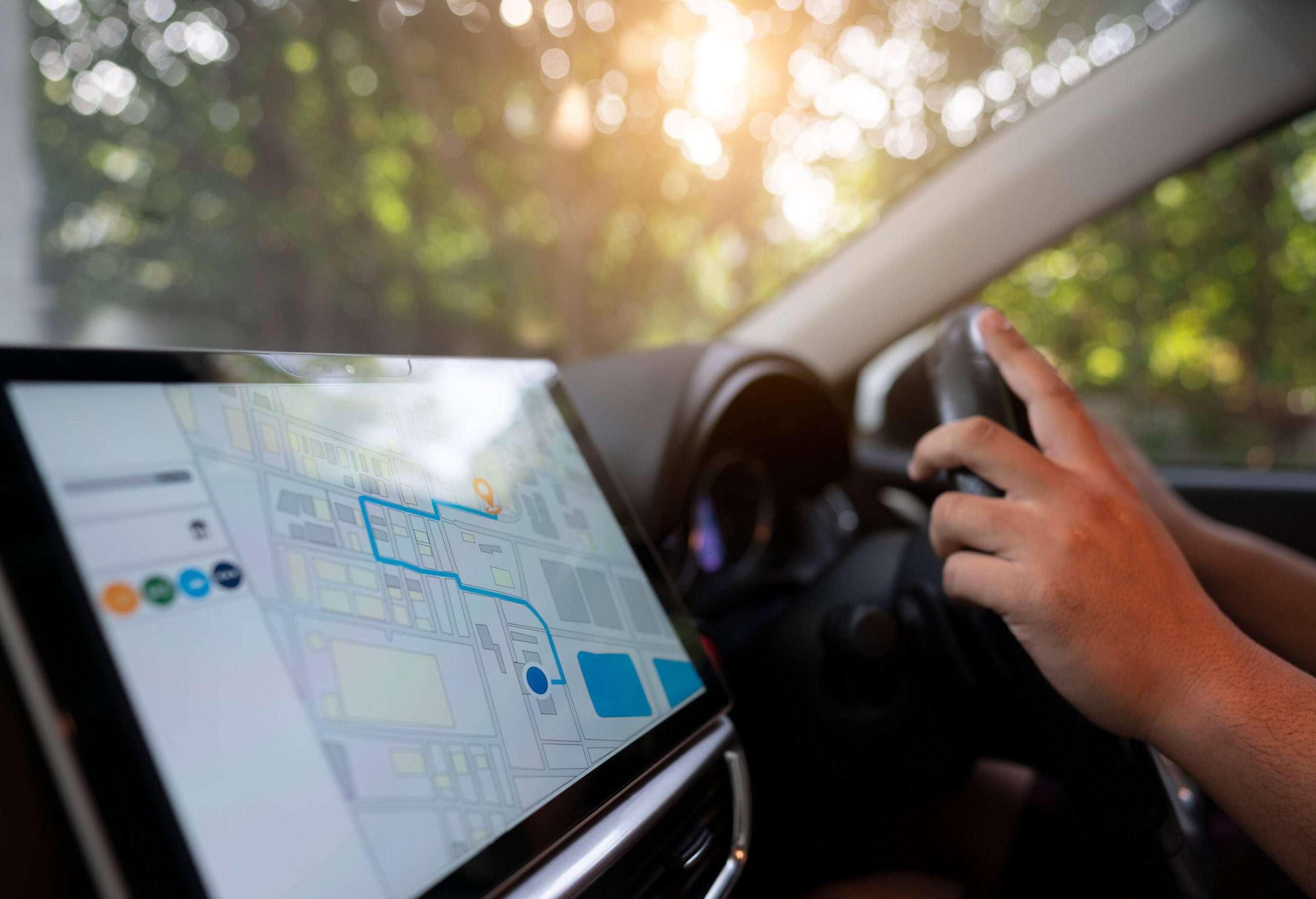 A hand navigates a car's steering wheel beside a screen with a GPS map.