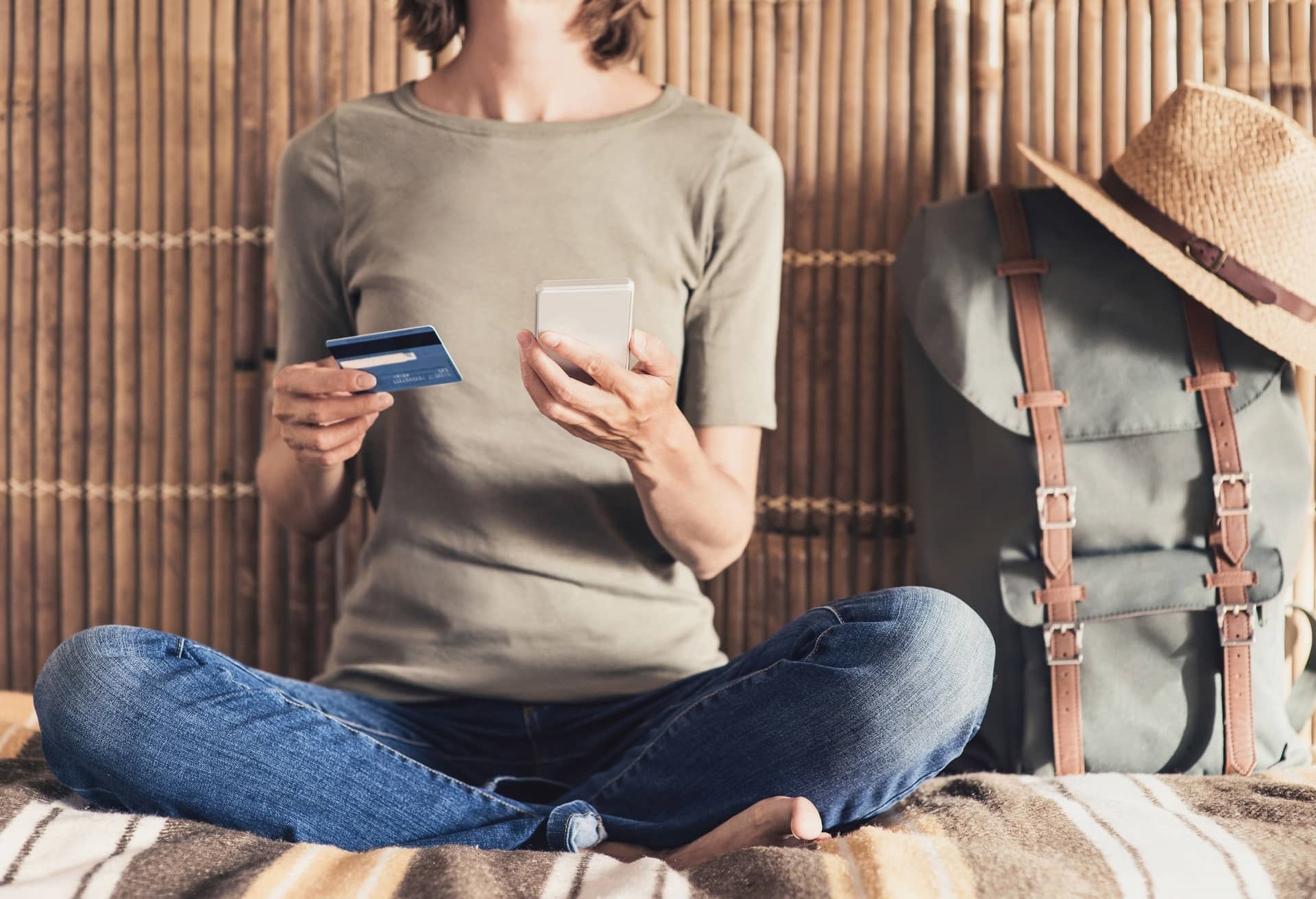 Young woman on vacations using phone and credit card. Online shopping concept THEME_TRAVEL_GettyImages-698025966