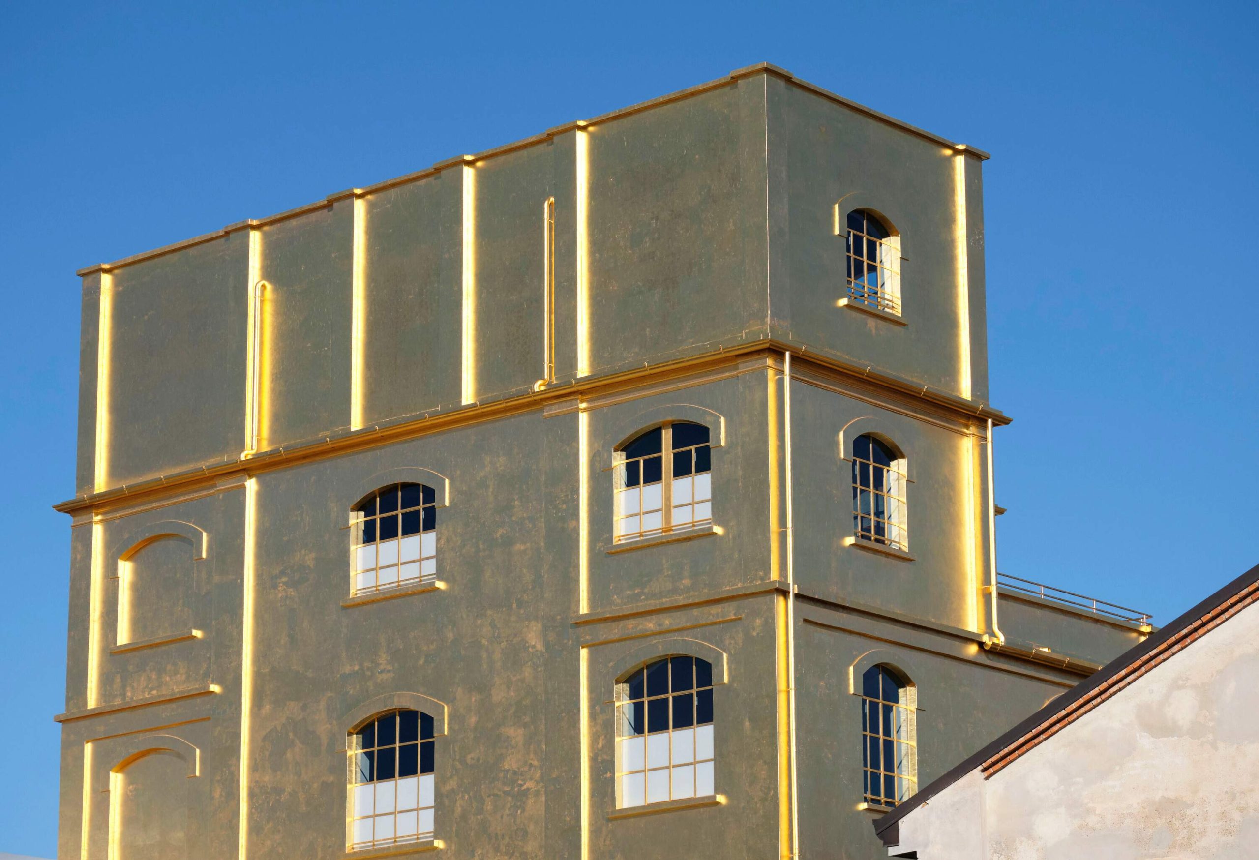 The upper part of Fondazione Prada, with its granite grey facade and elegant arch windows, showcases the sleek and modern architectural design.