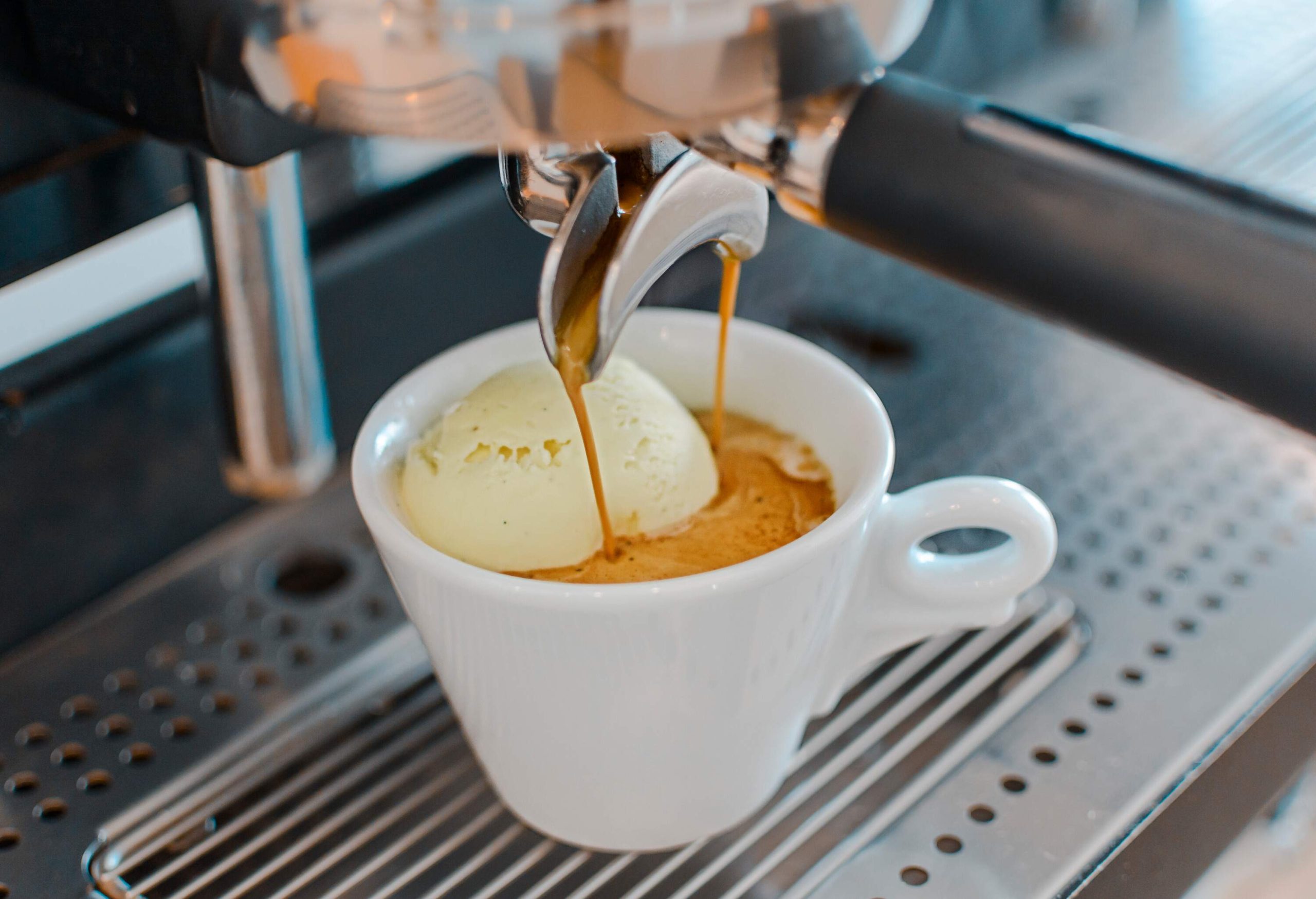 A white cup full of coffee from an espresso machine.