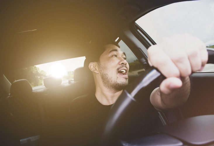 A man singing in a car while driving