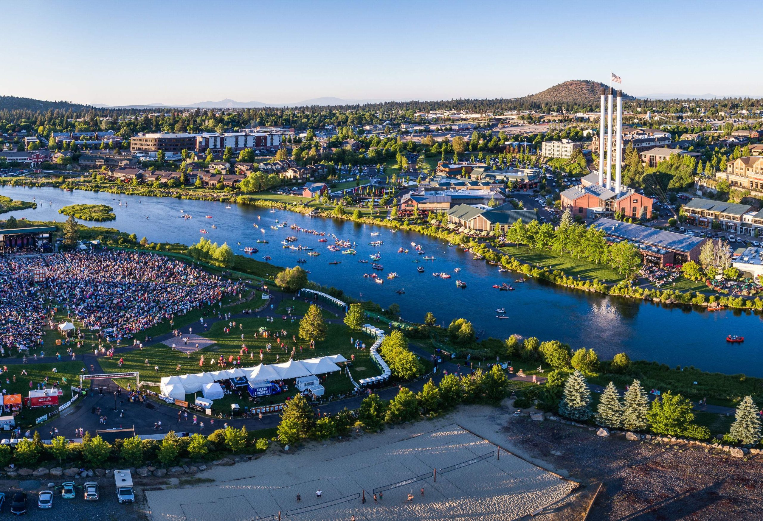 A river across the urban landscape of a small city and a crowded concert ground.
