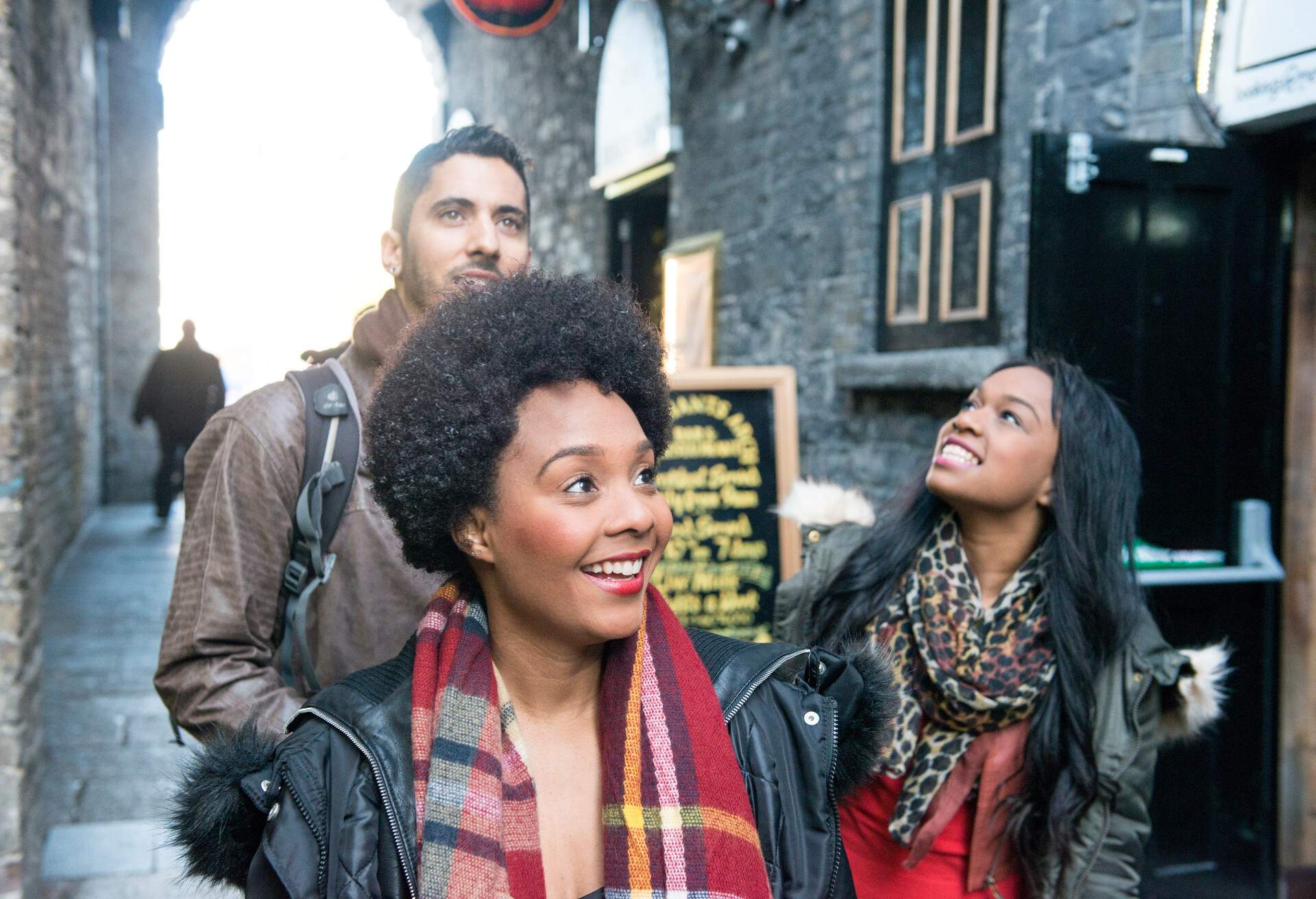 Three people looking around in a narrow alleyway.