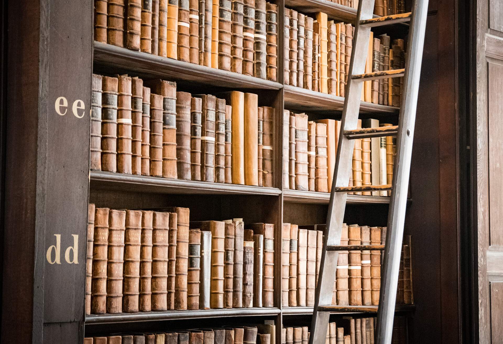 A bookshelf filled with books next to a ladder.