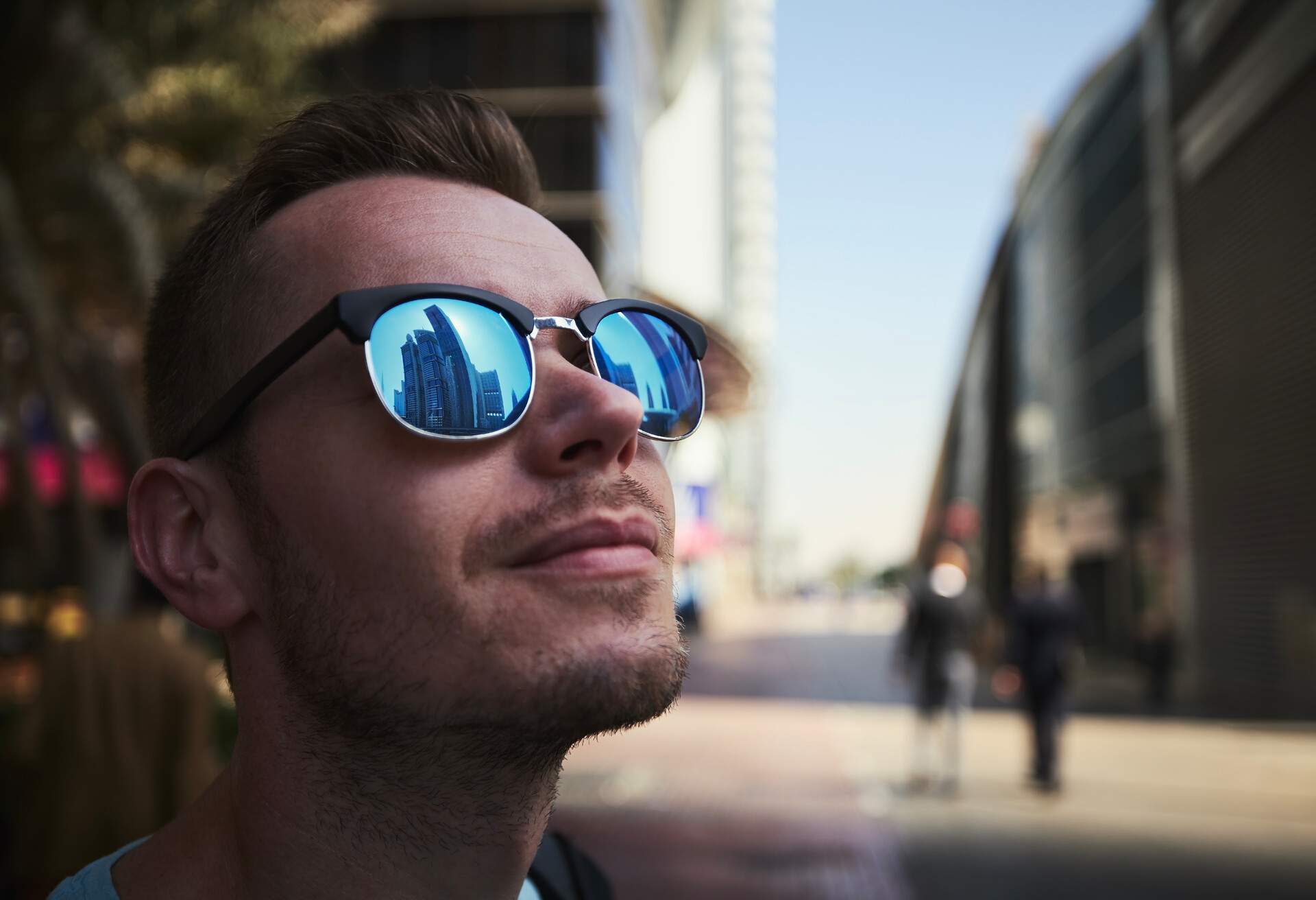 A man with sunglasses that reflects the towering skyscrapers.