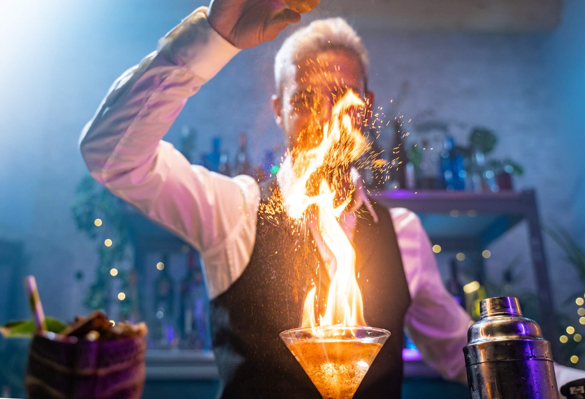 A burning cocktail drink in front of bartender.