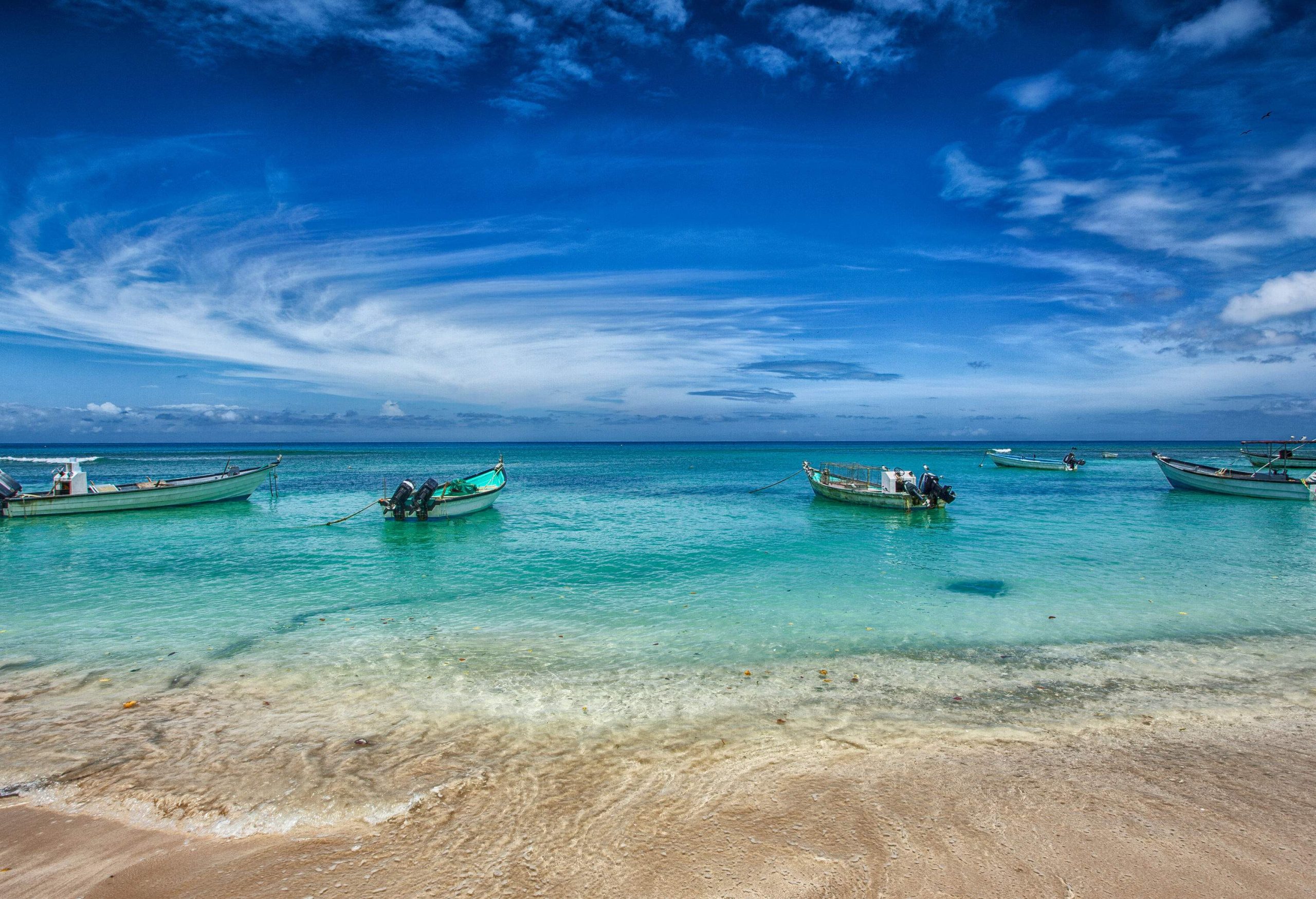 Empty fishing boats peacefully moored by the shore, with the vast expanse of the sea stretching into the horizon, while swirling clouds added a touch of drama to the tranquil scene.