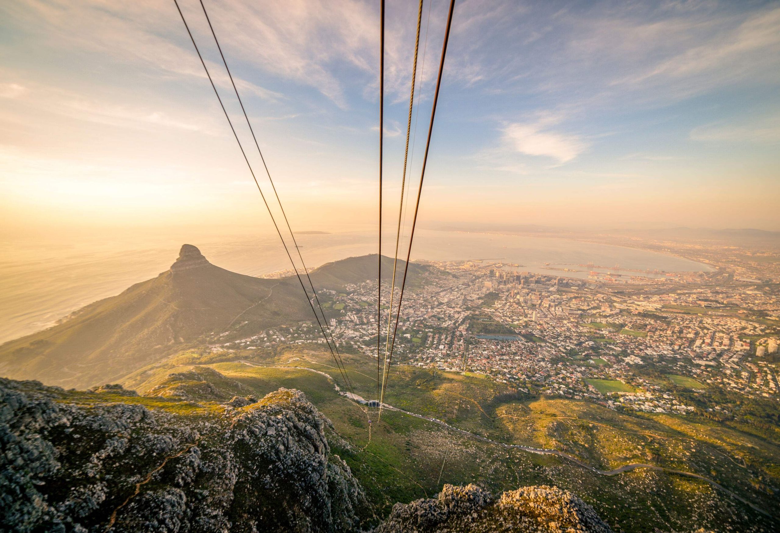 An empty ropeway running over the mountains, with a populous valley in the backdrop.