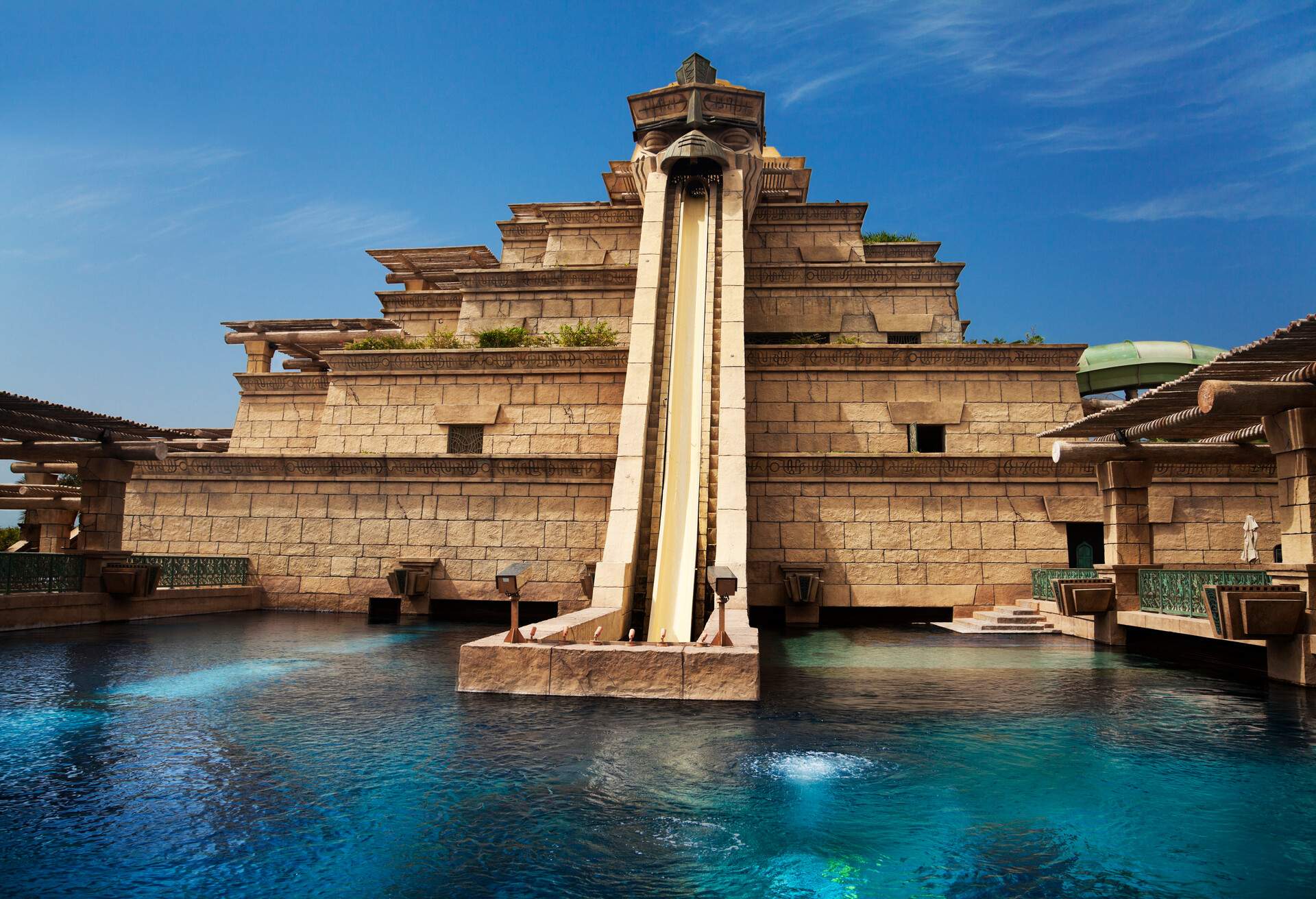 A terraced building with a giant slide into a large pool.