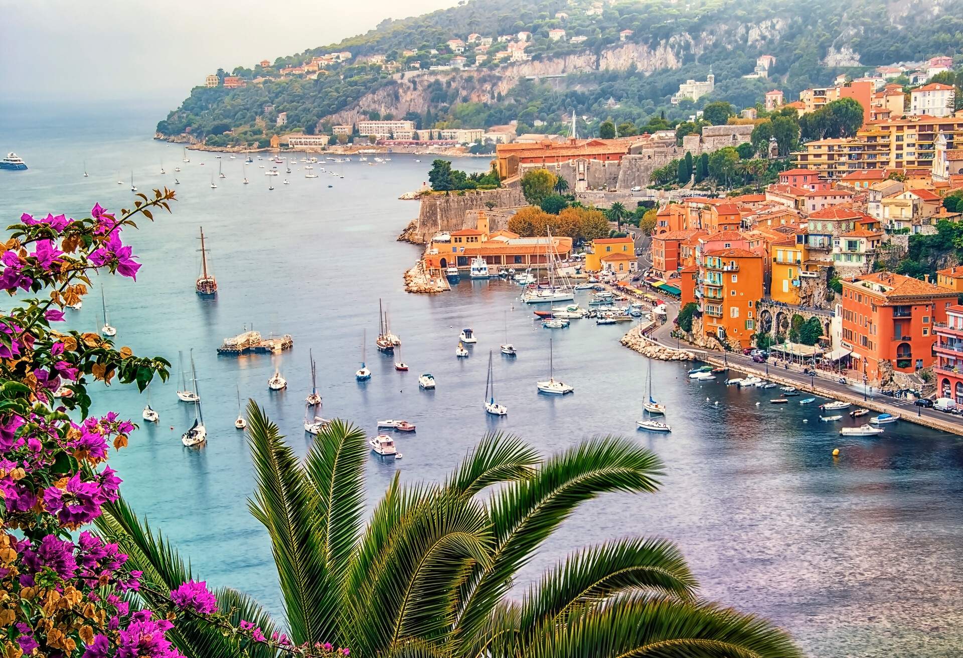 Aerial view of a scenic resort town with colourful classic buildings by the sea with moored yachts.