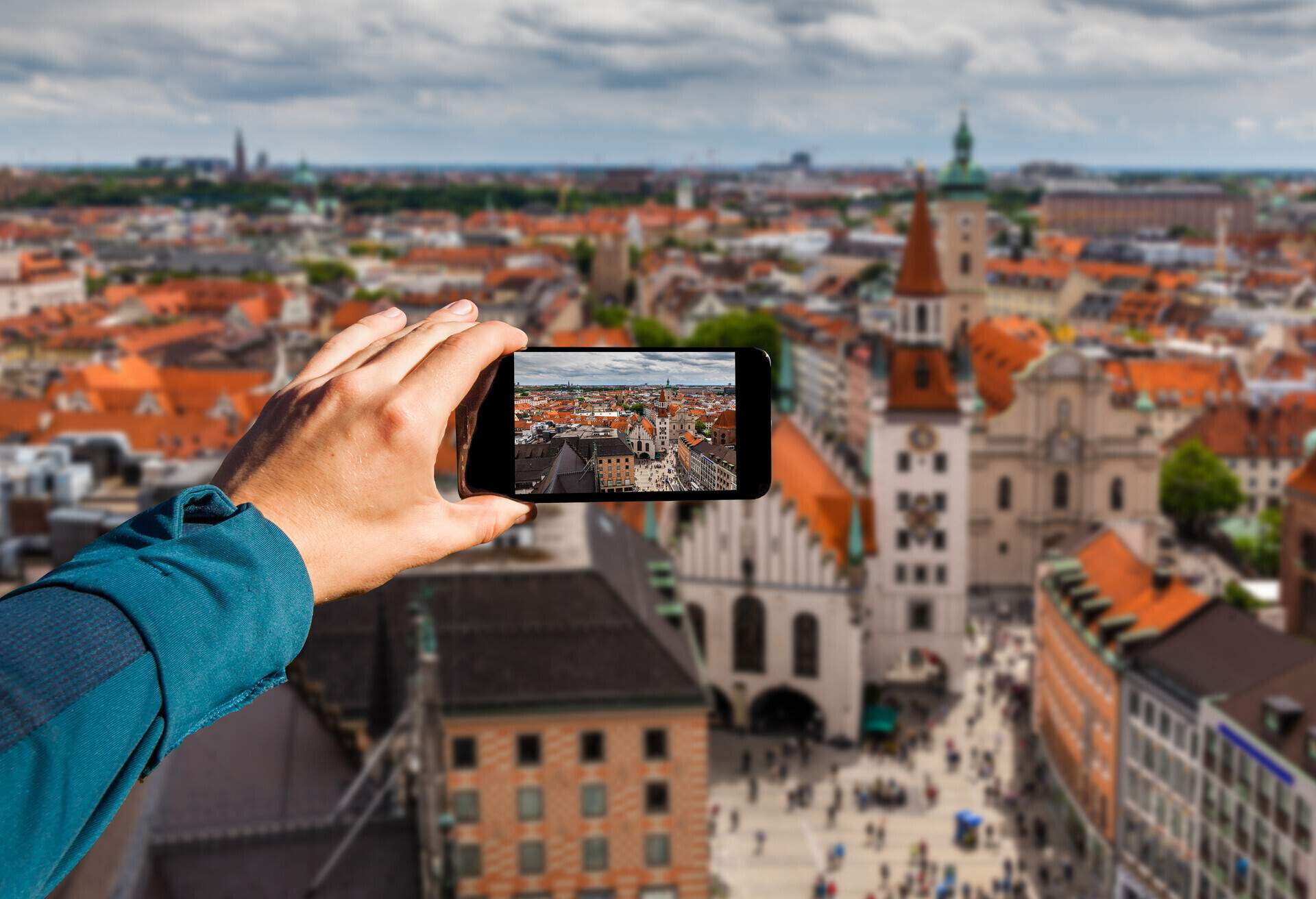 An individual holding a smartphone takes a photo of the old urban cityscape.
