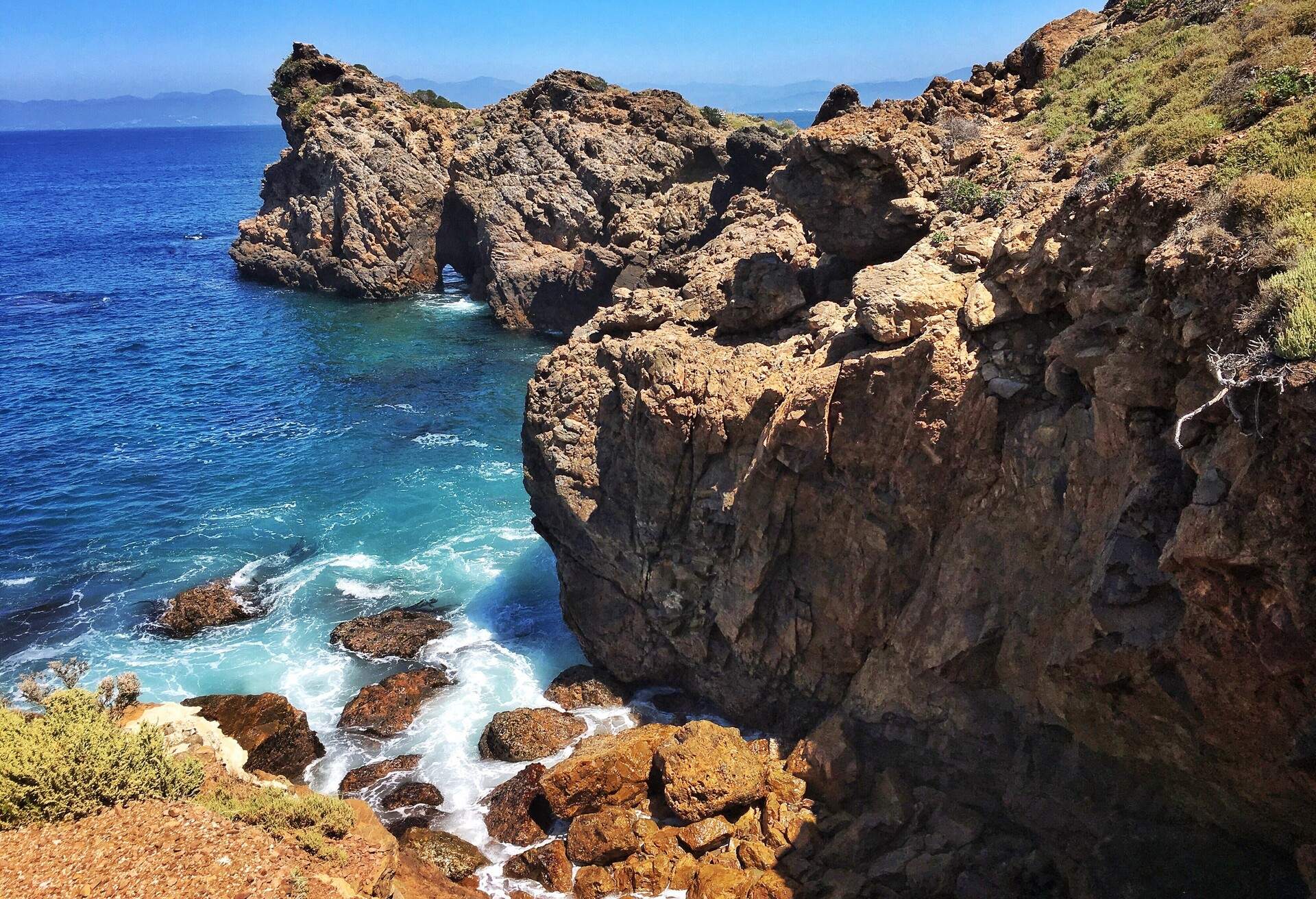 A rocky sea cliff with waves pounding on coastal rocks.