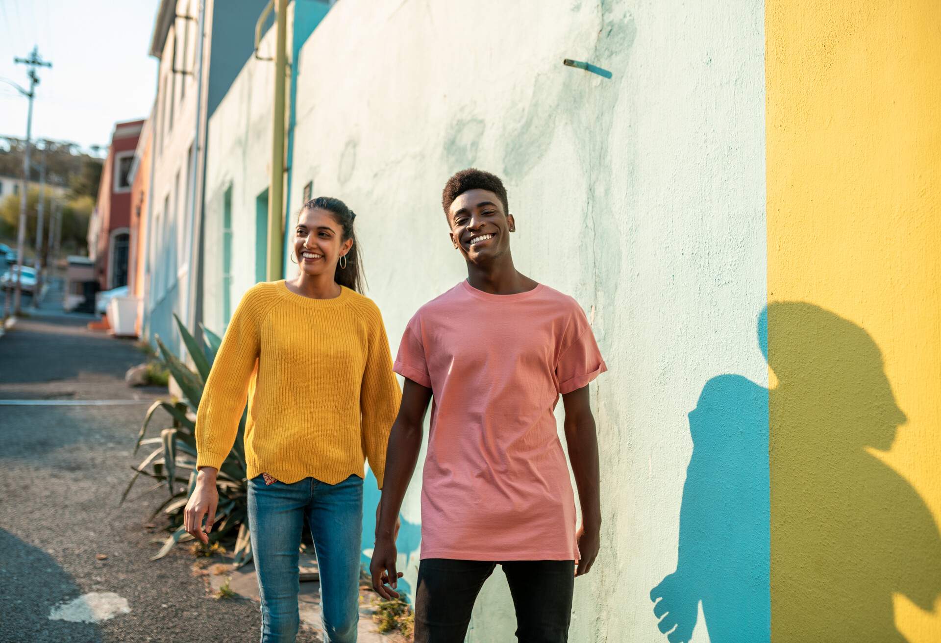 A charming couple walking together along colourful buildings.