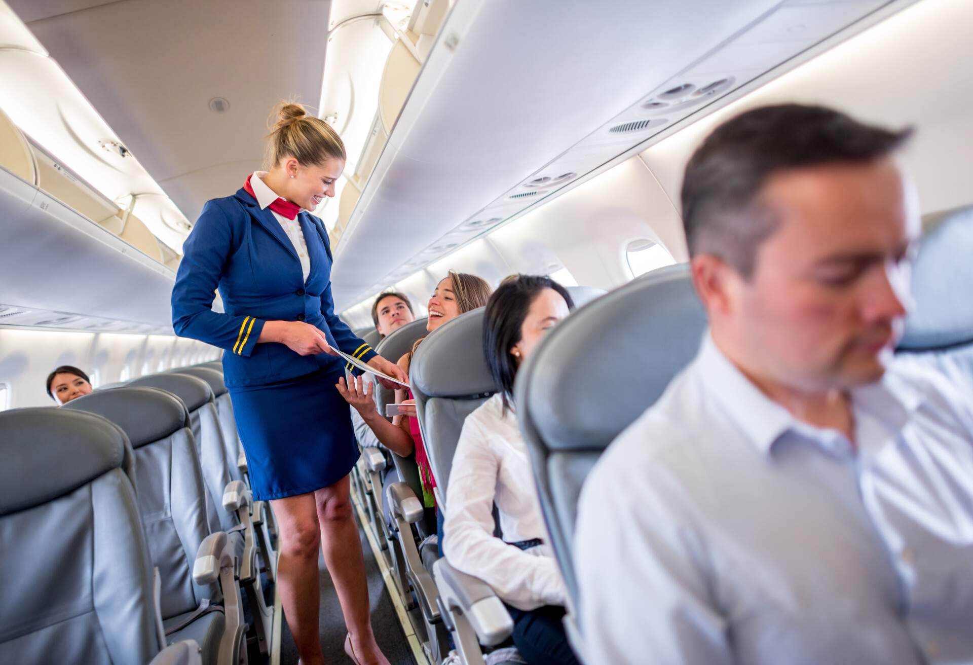 A friendly flight attendant attentively shows a list to a passenger, assisting them with care and professionalism.