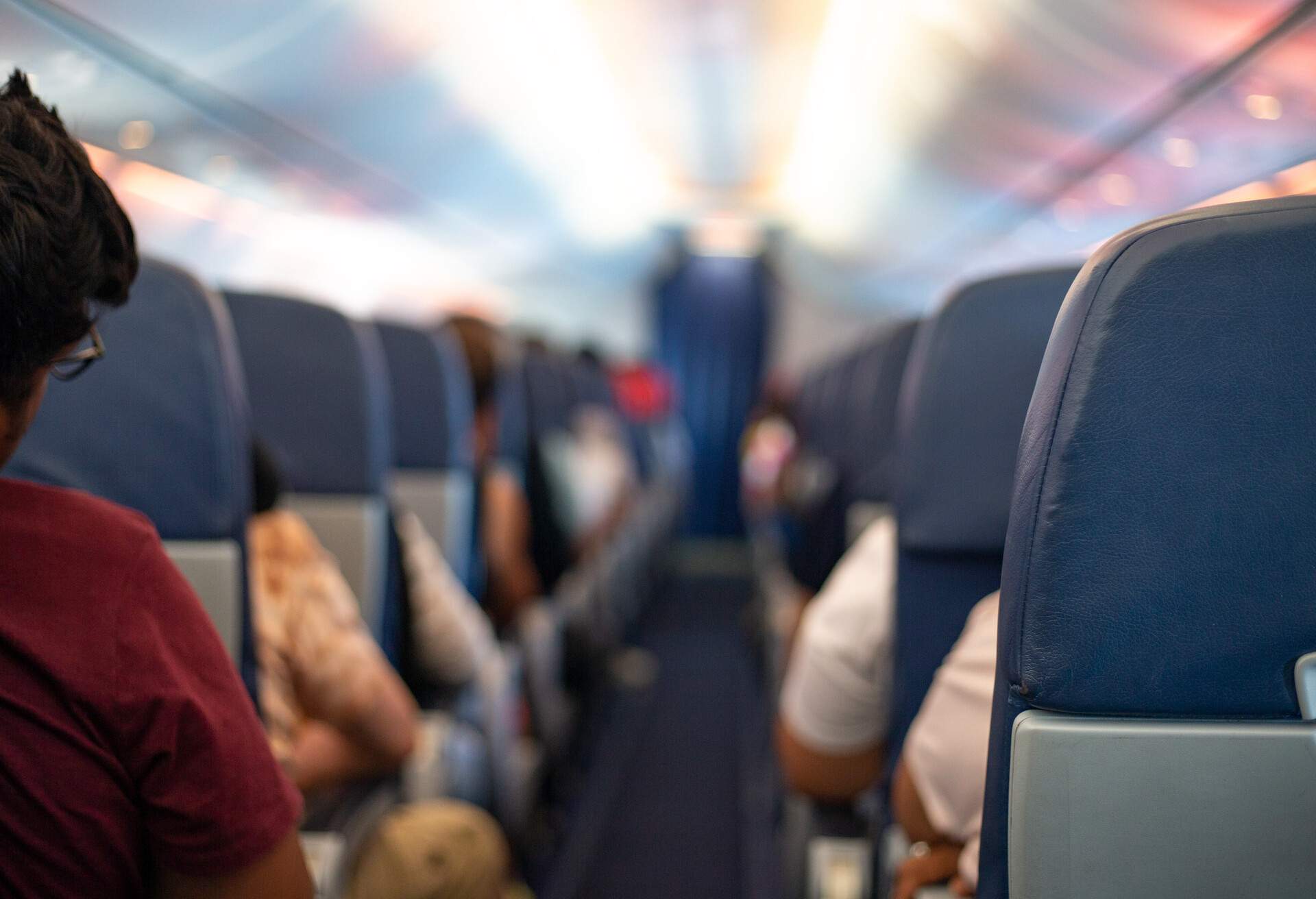 An empty airplane aisle with passengers comfortably settled in their seats.