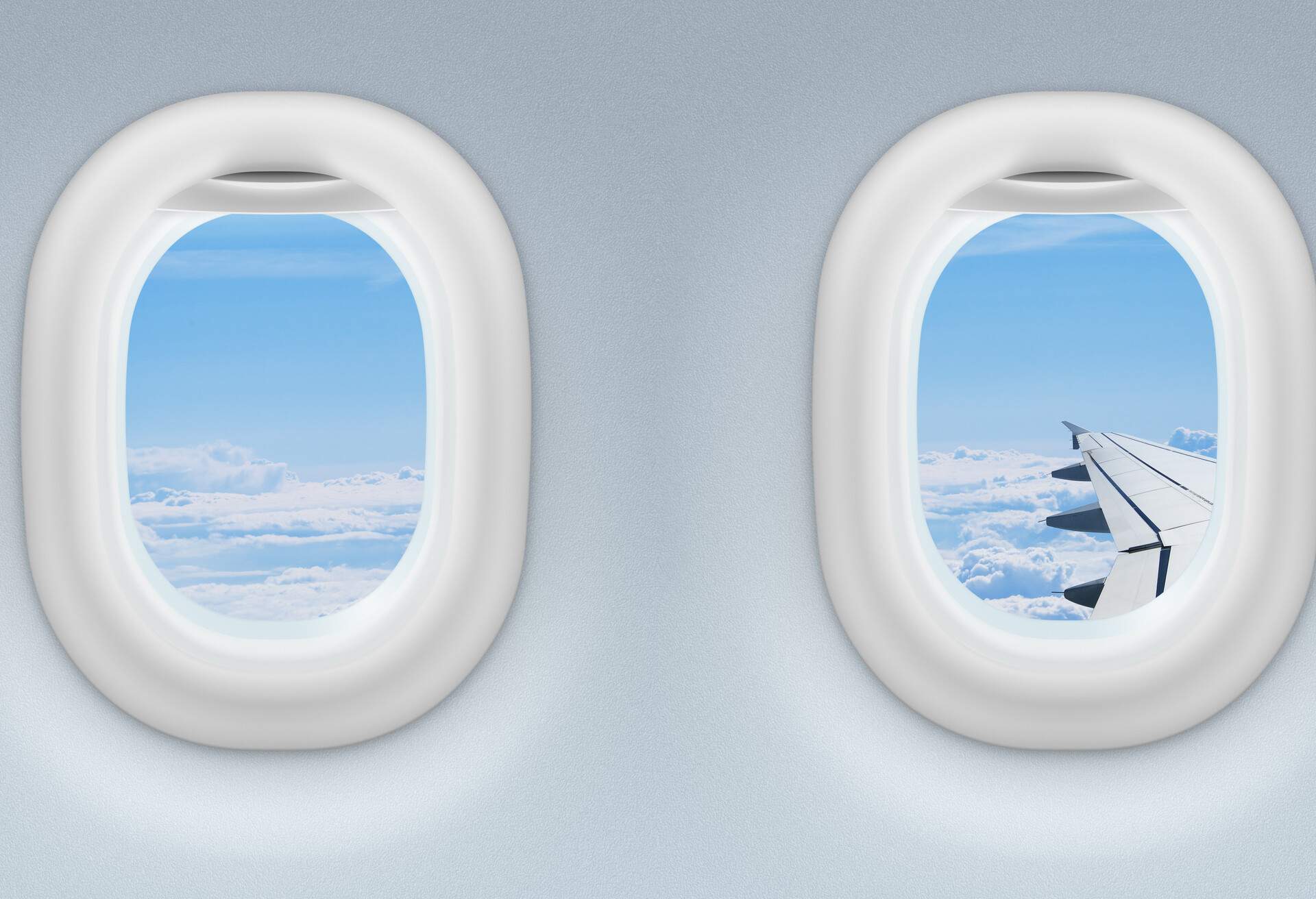 Oval-shaped airplane portholes with the shades drawn up, showing a beautiful cloudscape.