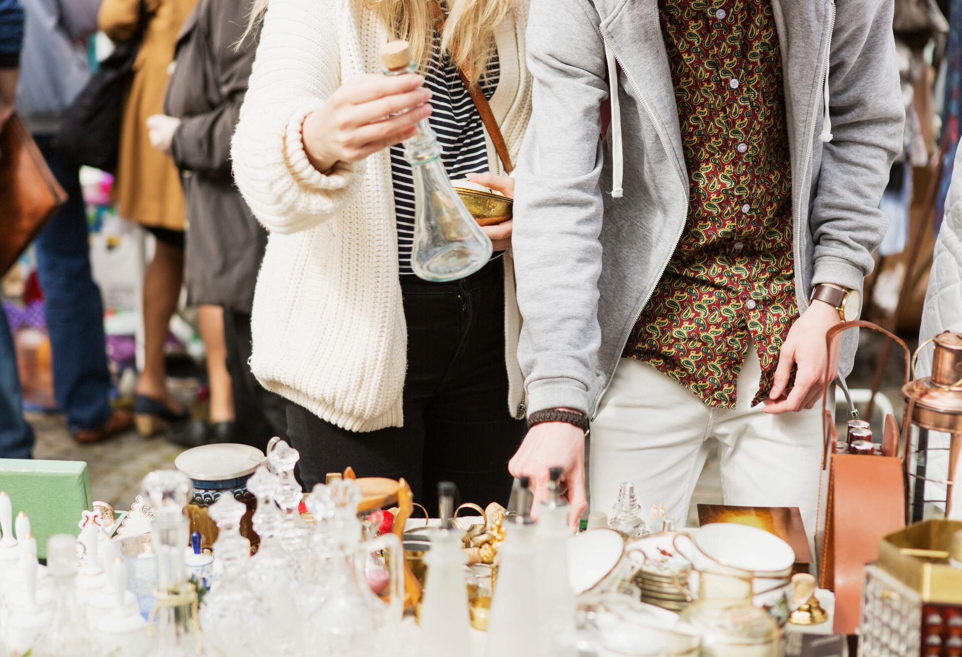 Two people browsing through a vintage display at a flea market.