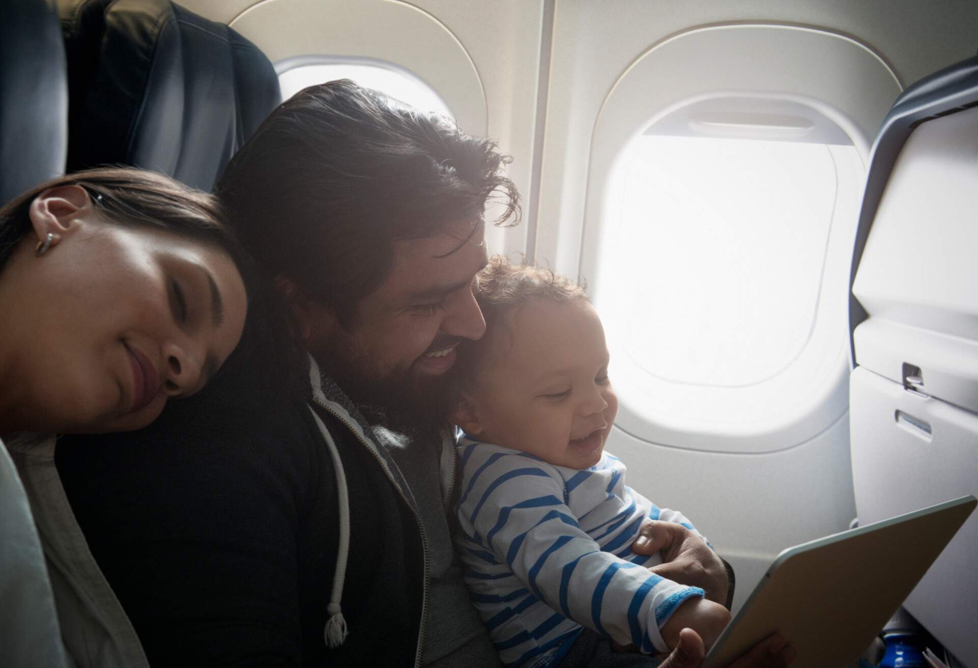 A happy couple with their toddler sitting inside the aeroplane.