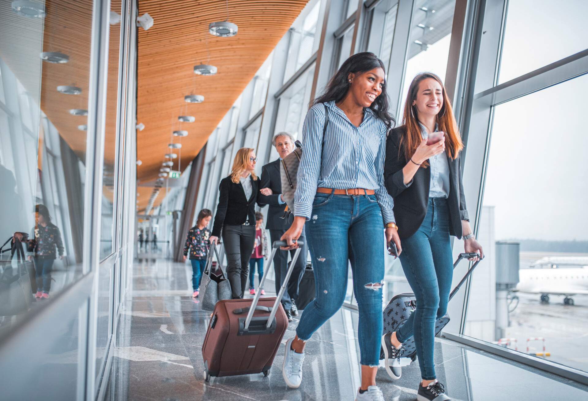 Random passengers dragging their luggage through an airport terminal.