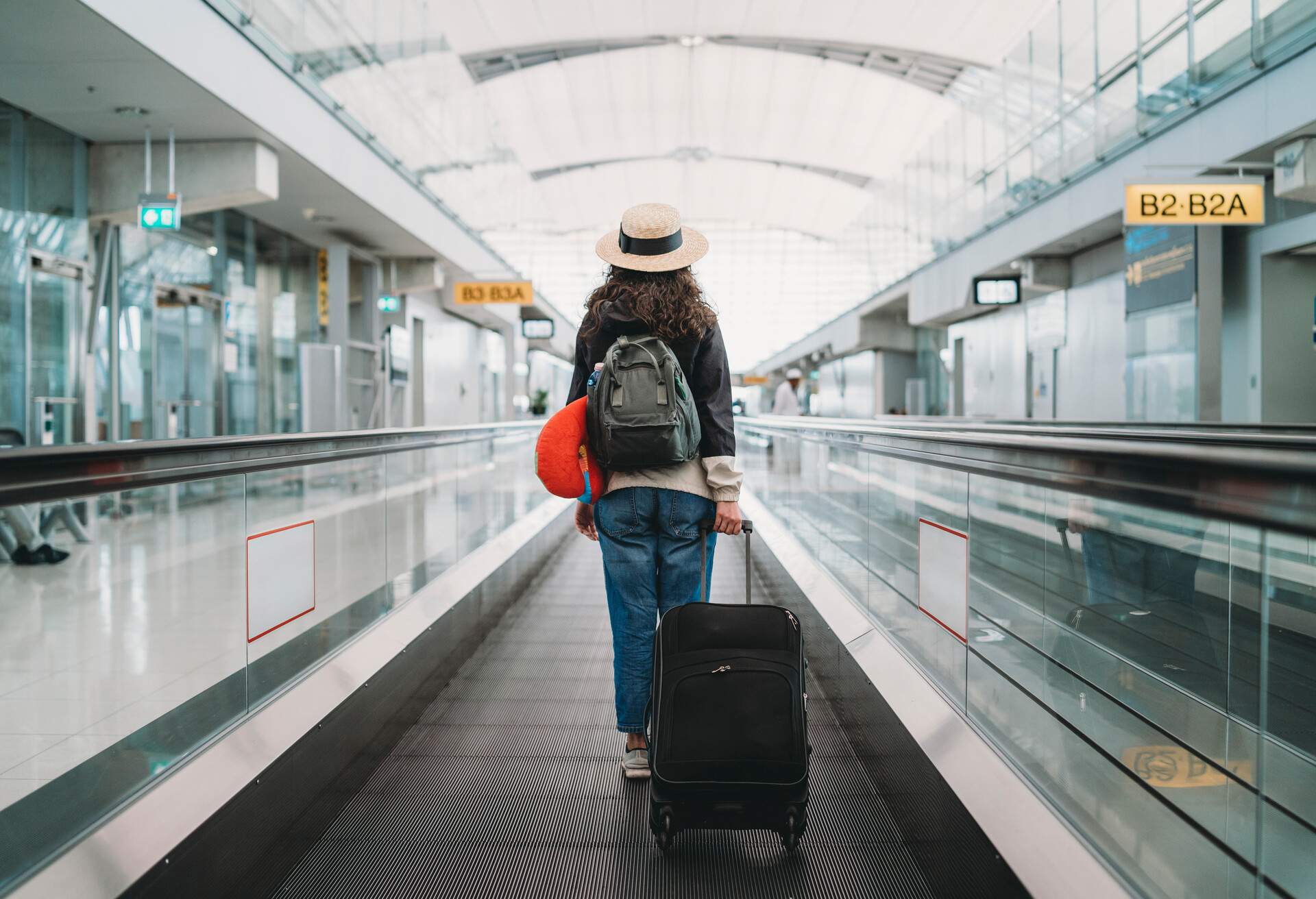 A woman with her suitcase in a travelator at an airport.