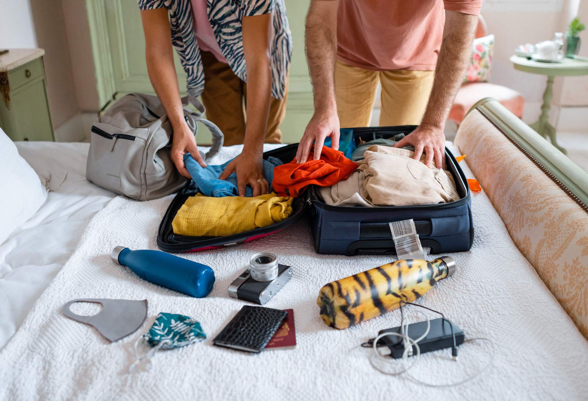 Two individual packs their stuff laid in bed inside a suitcase.