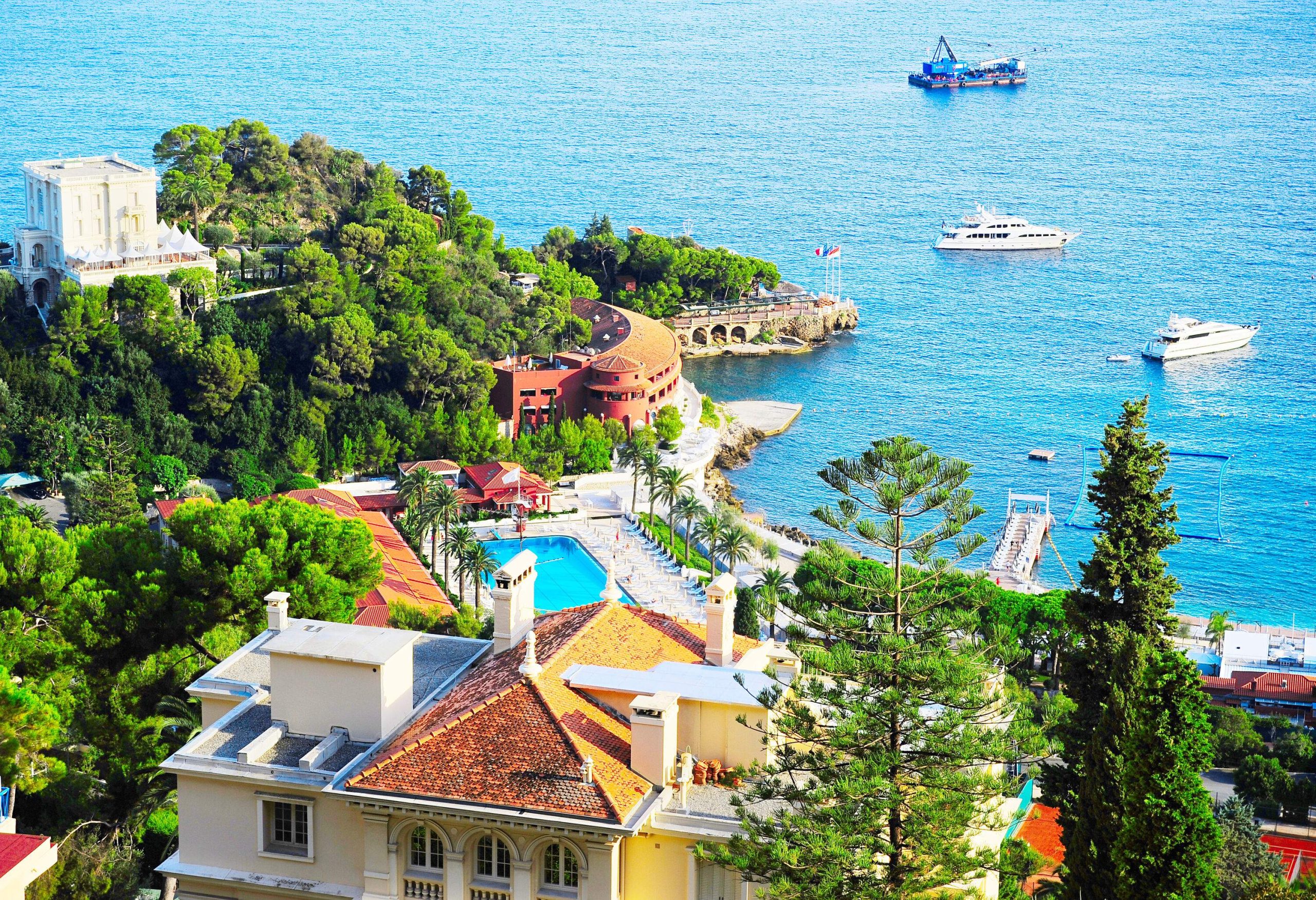A destination resort with beautiful villas overlooking the boats sailing across the blue sea.