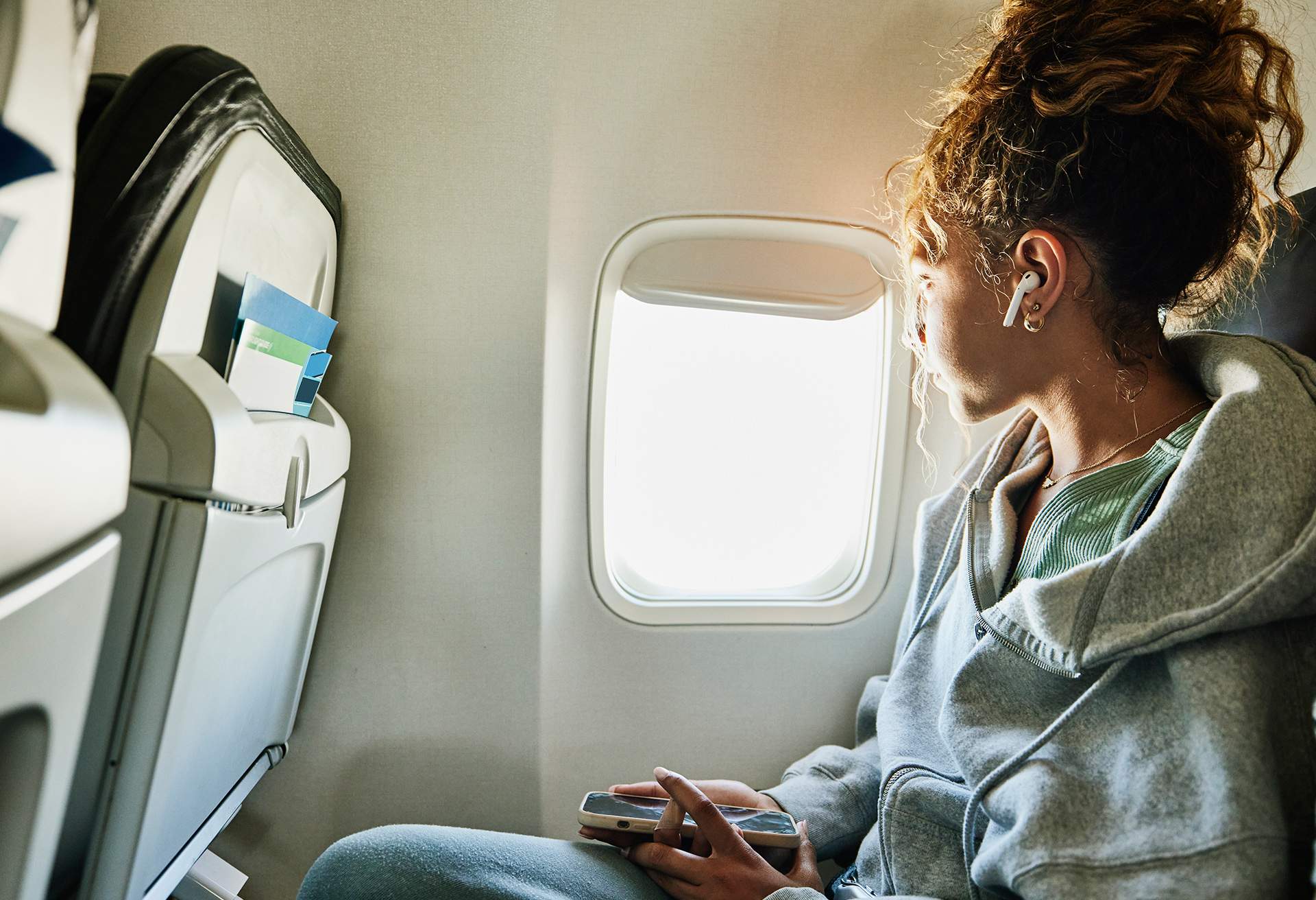 A lady looking out window of commercial airplane