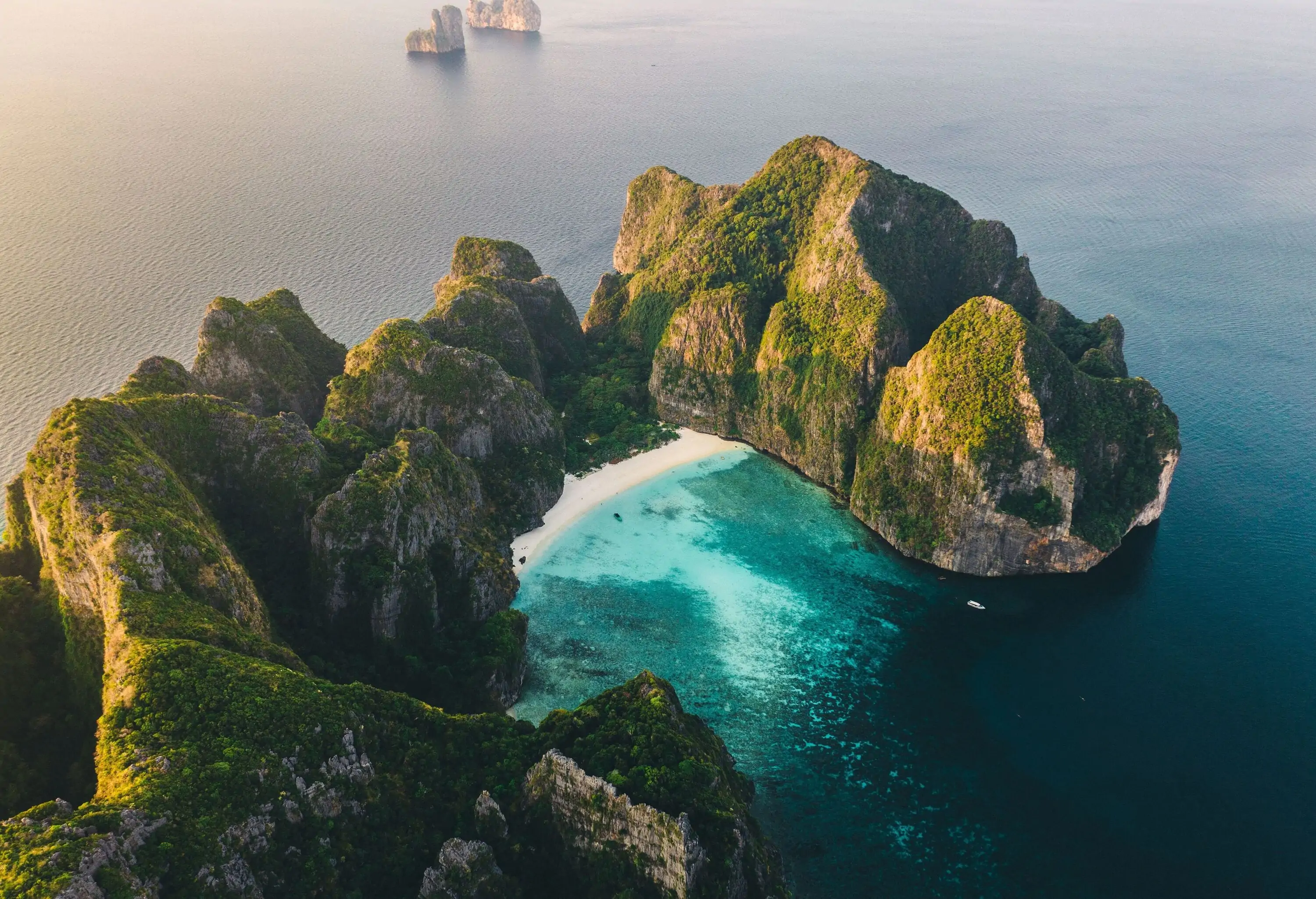 A stunning cove beach with clear turquoise water encompassed by limestone karsts.