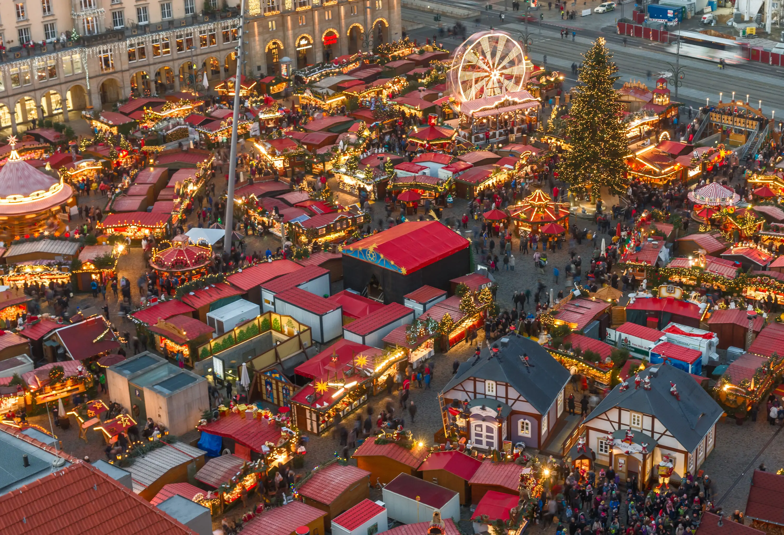 A collection of Christmas markets and holiday attractions in a brightly-lit town square.
