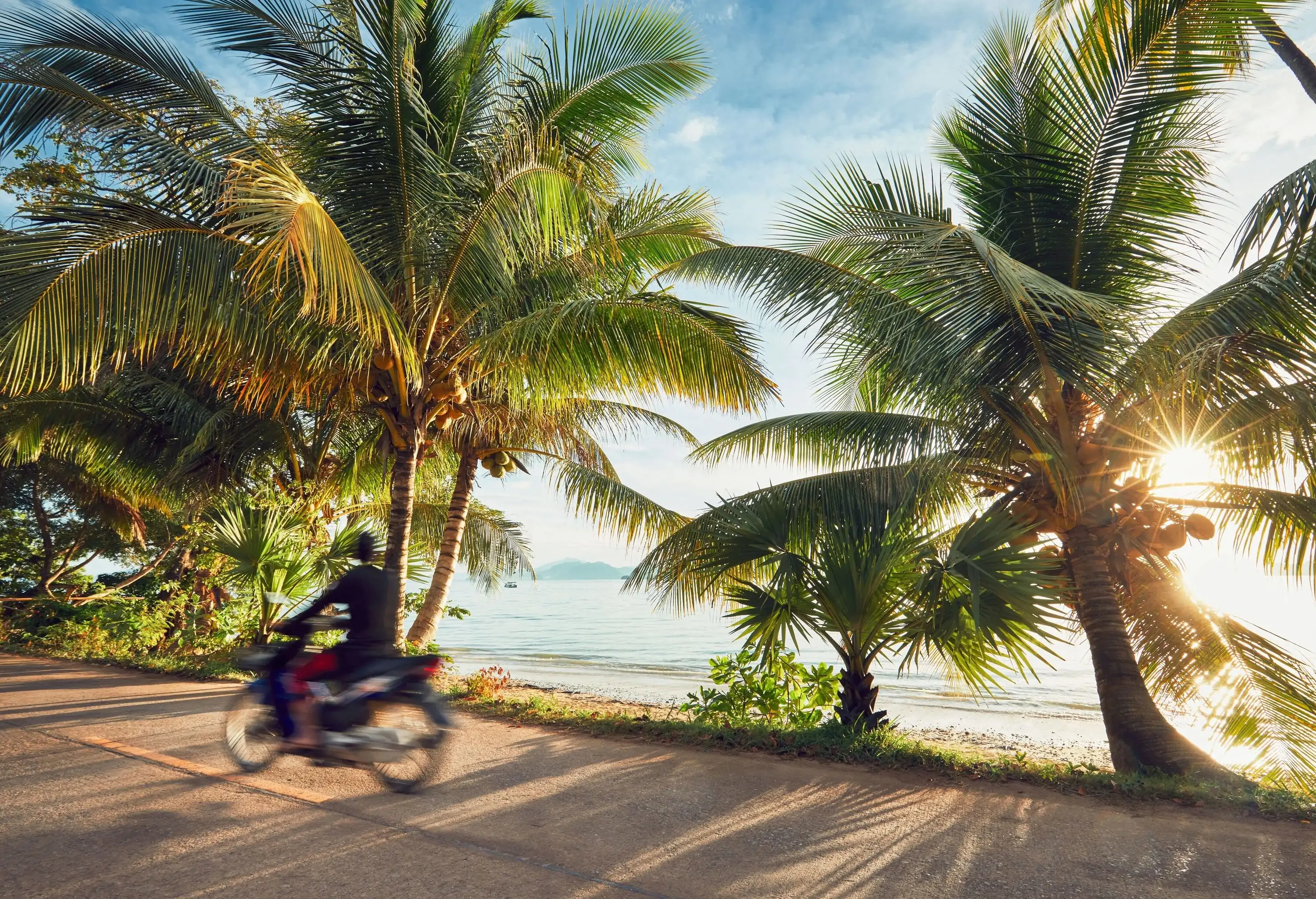 Tourist is driving motorbike on the tropical island at the sunrise. Koh Yao Noi, Thailand