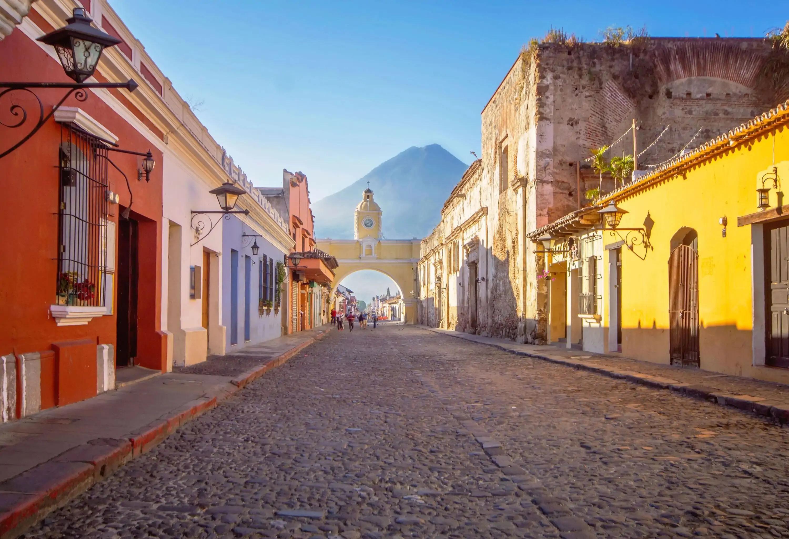 A cobblestone street with colourful classic houses and an iconic arched gate at the end.
