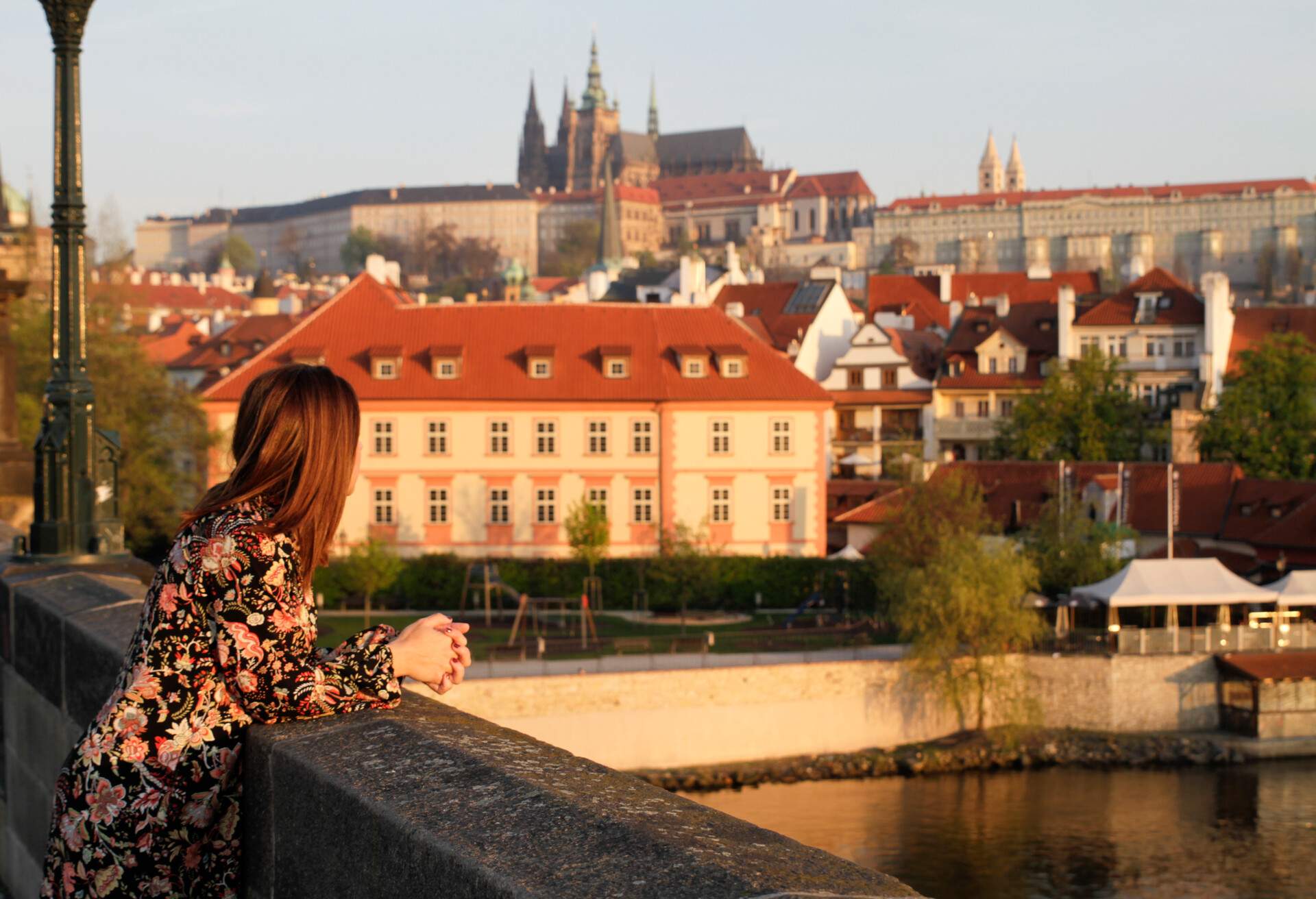 A woman leaning on a bridge wall, her gaze fixed on the stunning architecture.